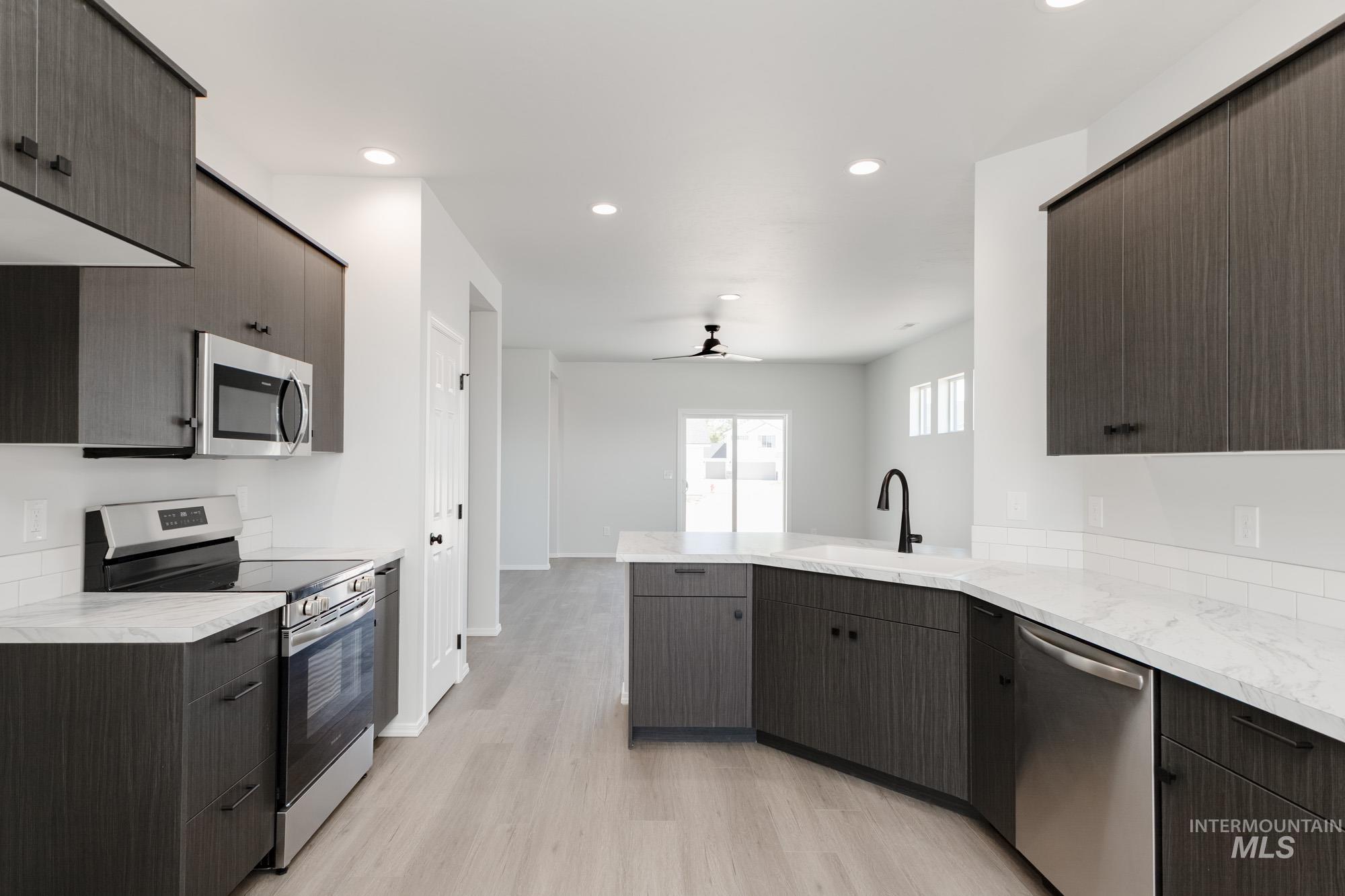 Kitchen featuring appliances with stainless steel finishes, modern cabinets, light wood-type flooring, recessed lighting, and ceiling fan