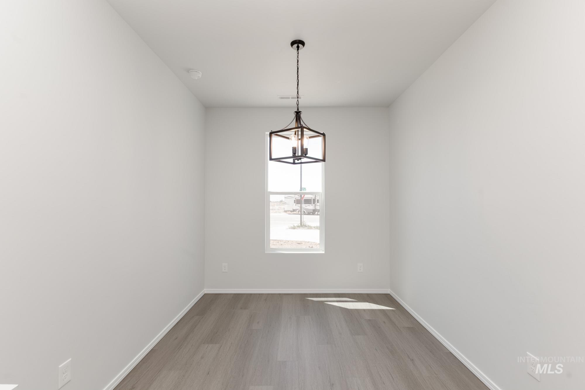 Empty room with light wood-style flooring and a chandelier