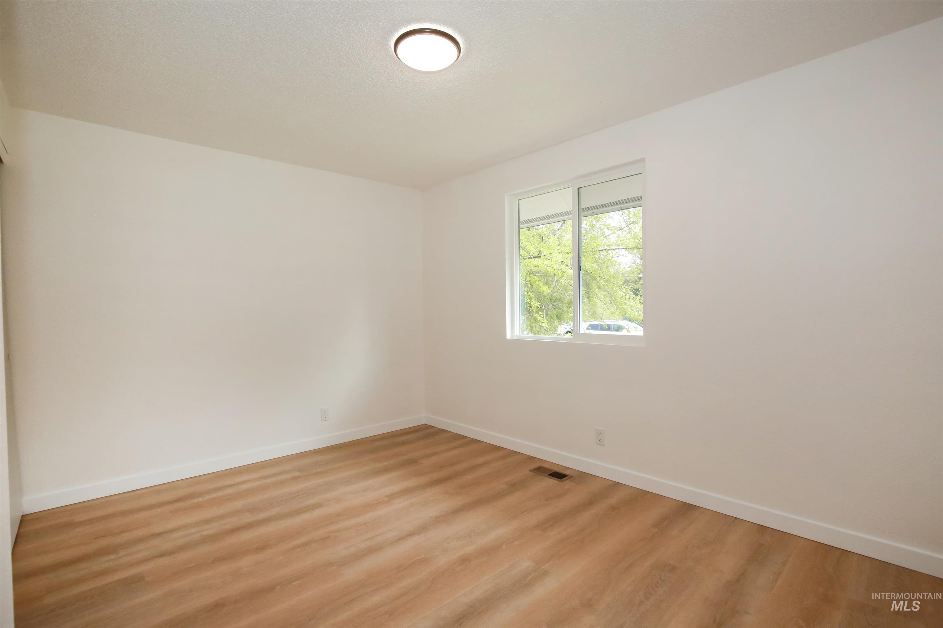 Spare room featuring baseboards and light wood-type flooring