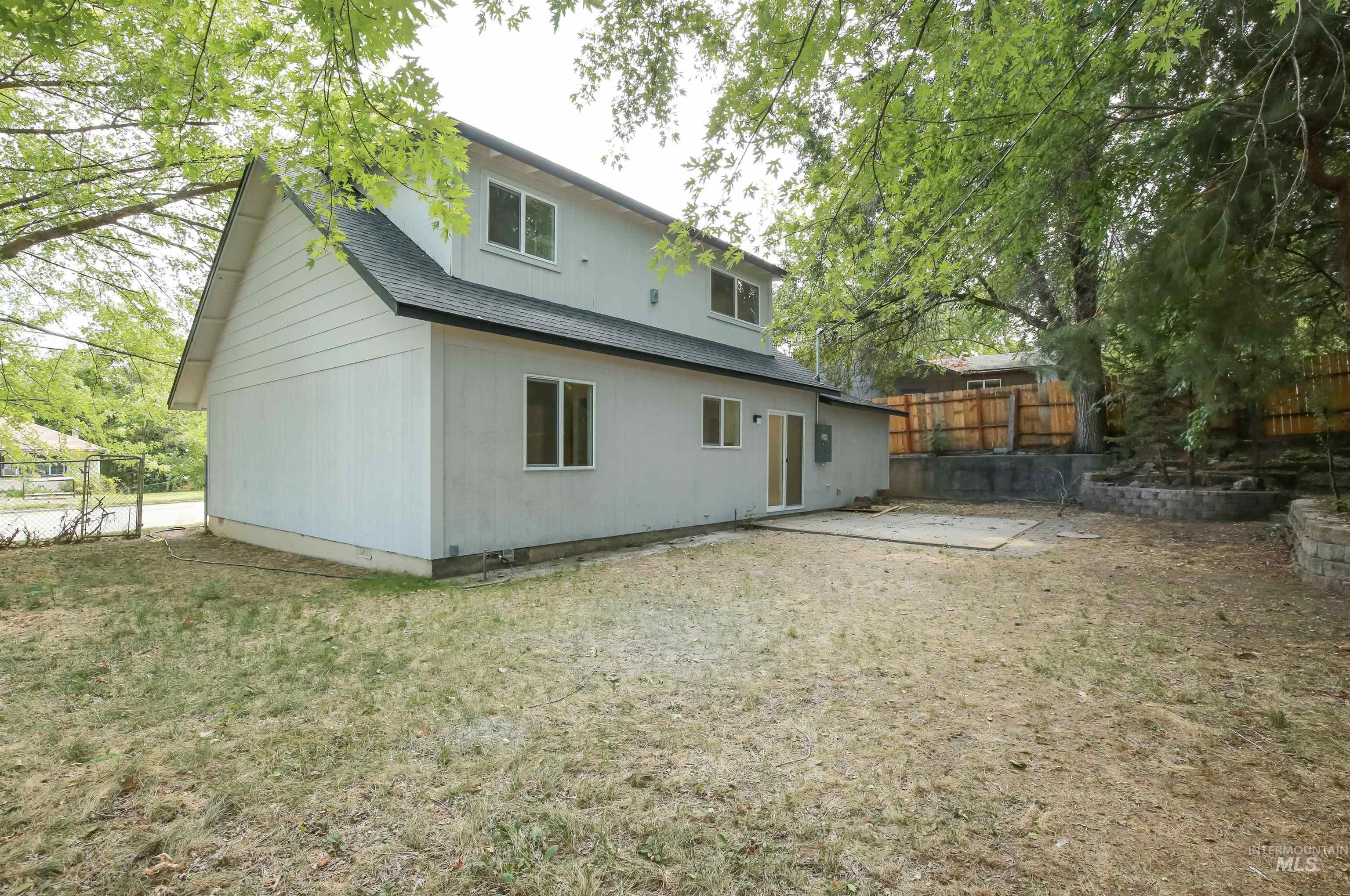 Rear view of house featuring roof with shingles and a patio