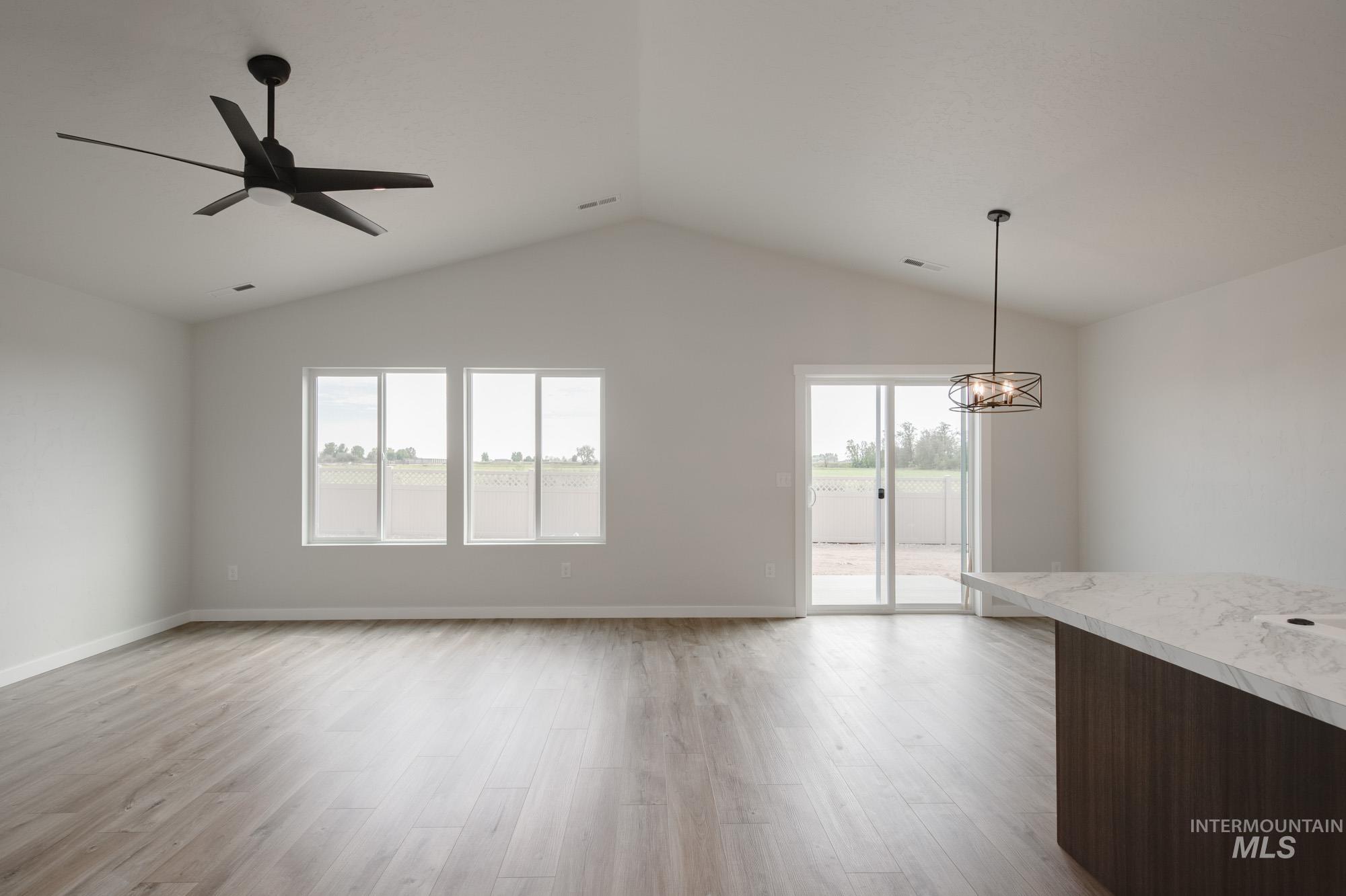 Unfurnished living room featuring light wood finished floors, lofted ceiling, and ceiling fan