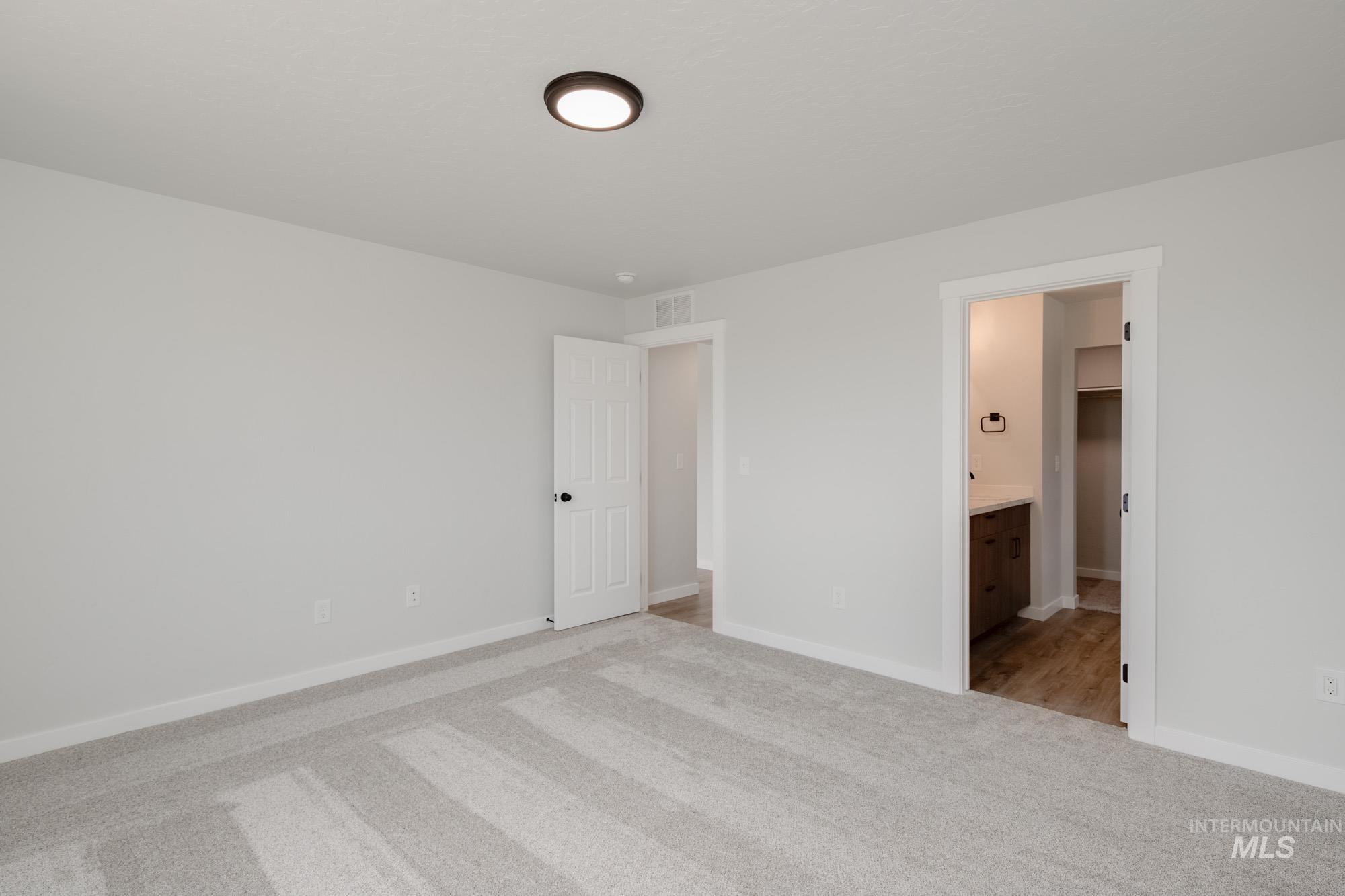Unfurnished bedroom featuring light colored carpet and ensuite bath