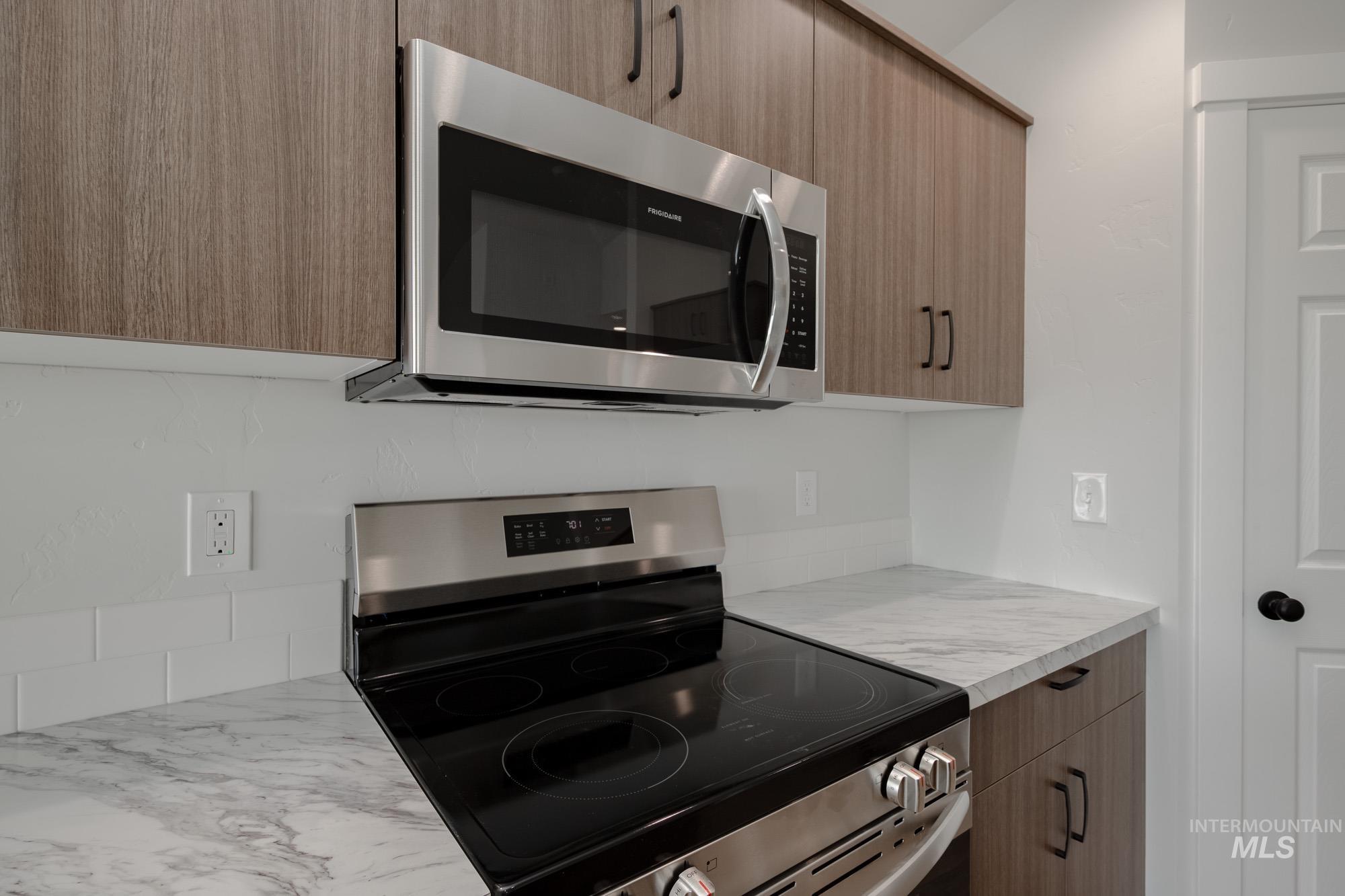 Kitchen featuring appliances with stainless steel finishes, modern cabinets, light countertops, and brown cabinets