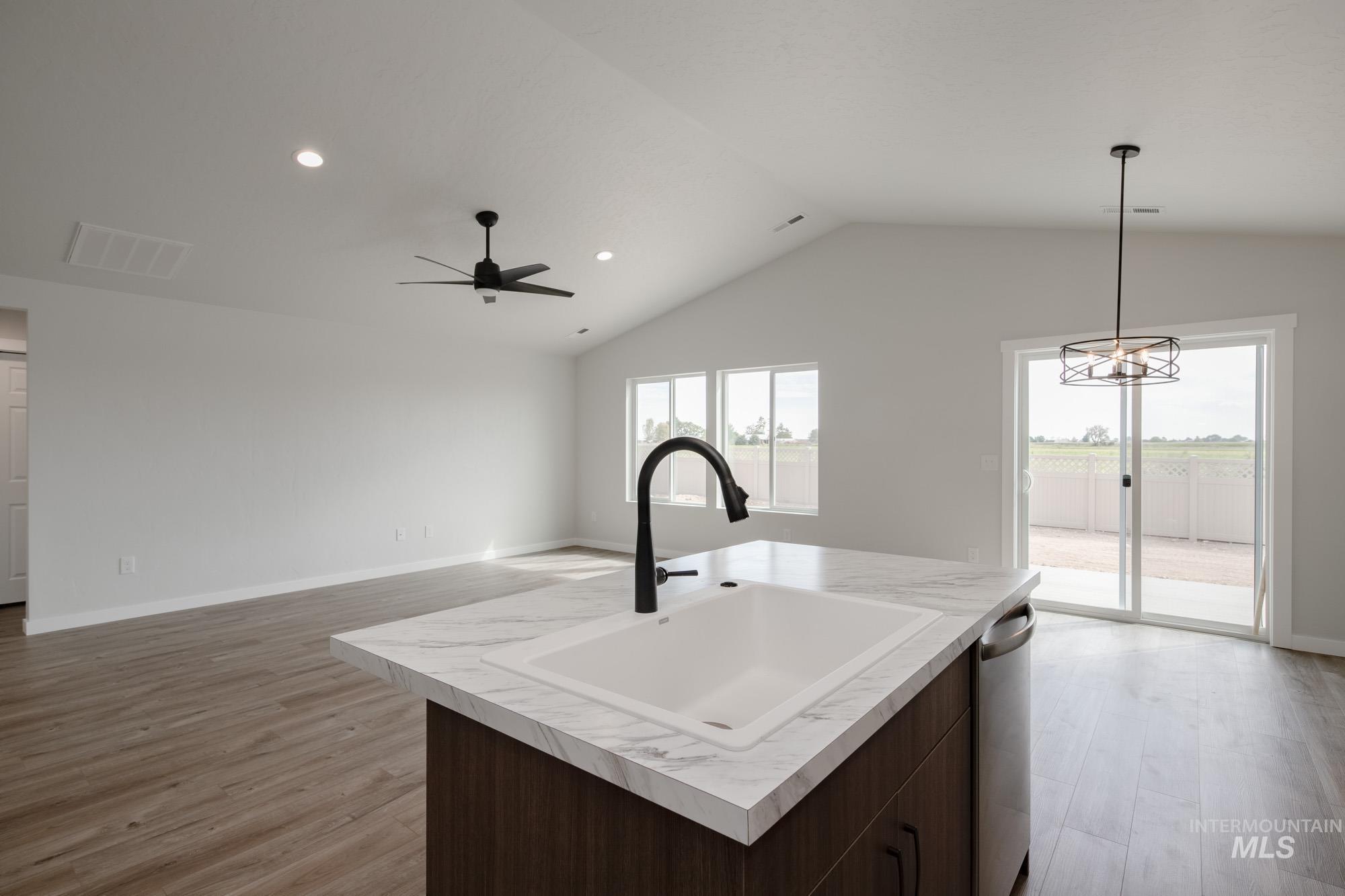 Kitchen with light countertops, light wood-style flooring, recessed lighting, decorative light fixtures, and vaulted ceiling