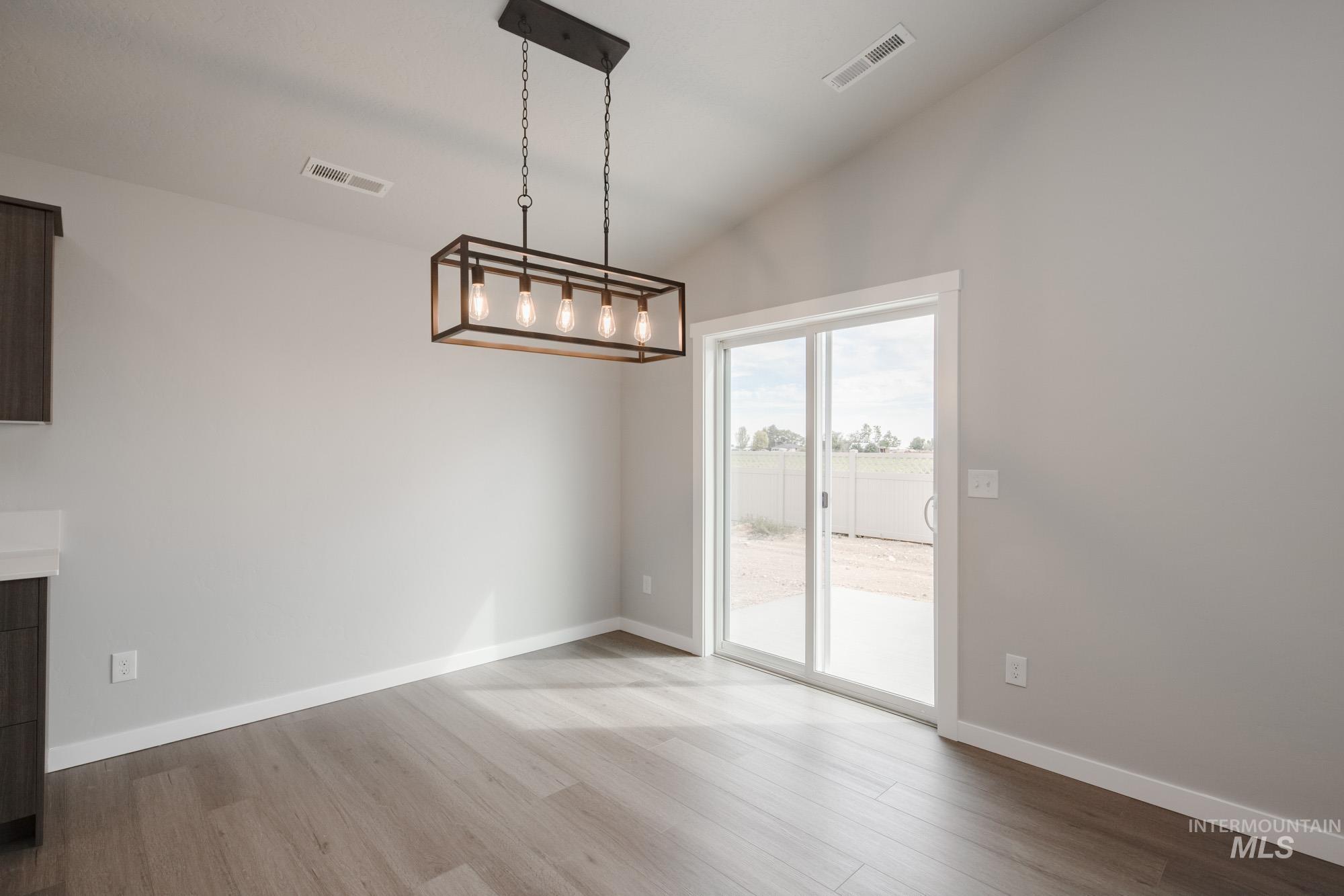 Unfurnished dining area featuring vaulted ceiling and light wood finished floors