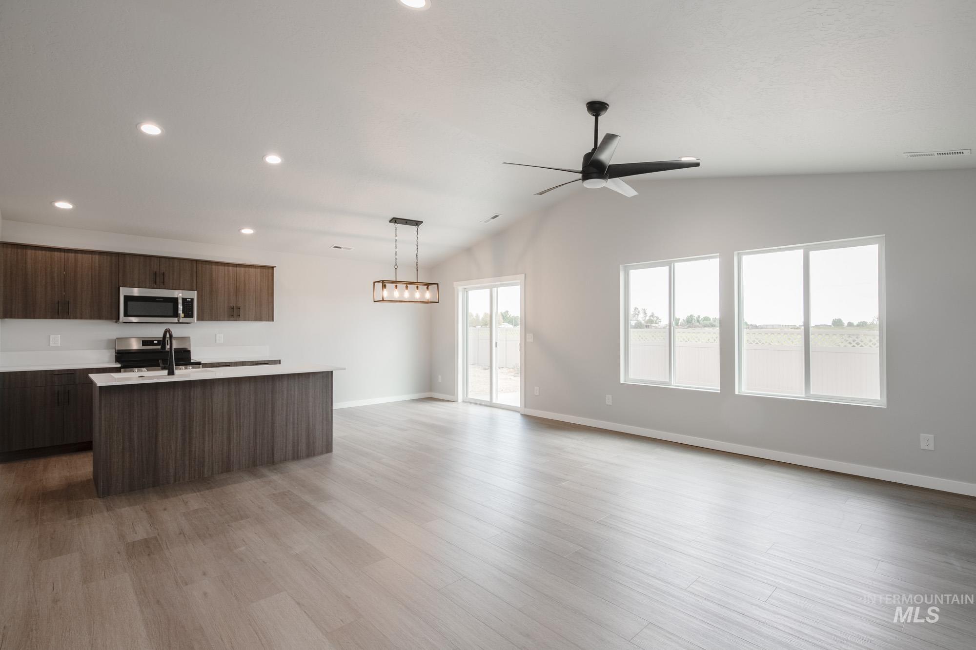 Kitchen with an island with sink, open floor plan, pendant lighting, vaulted ceiling, and modern cabinets