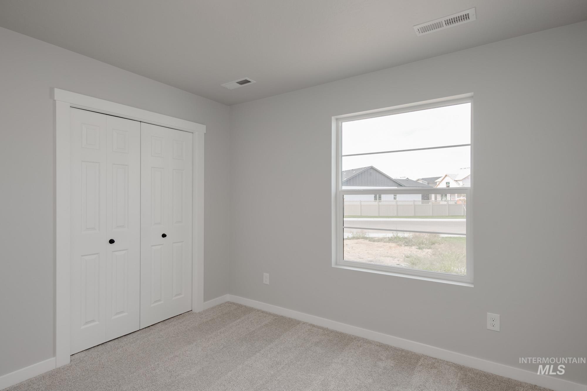 Unfurnished bedroom featuring light carpet and a closet