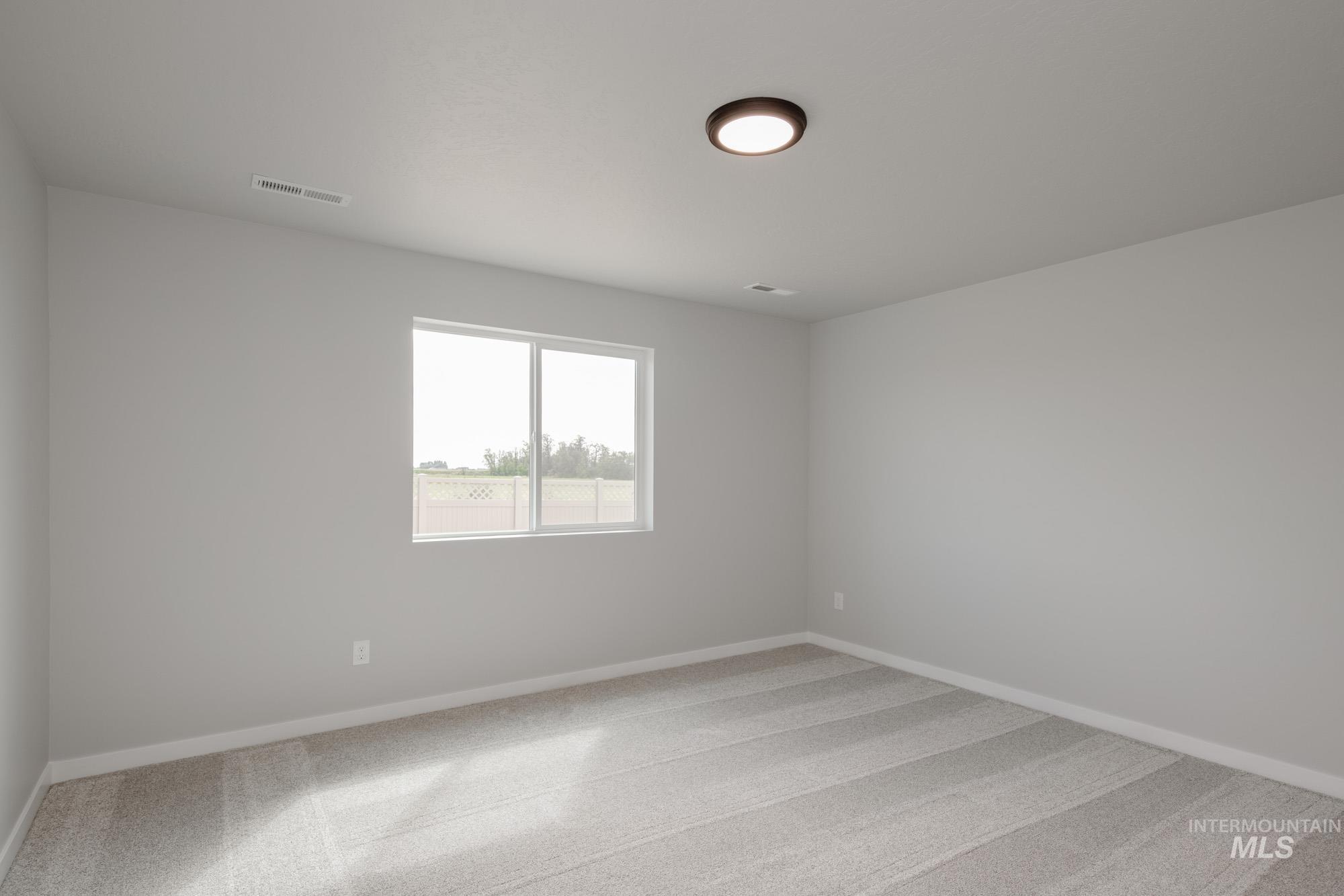 Empty room with light colored carpet and baseboards
