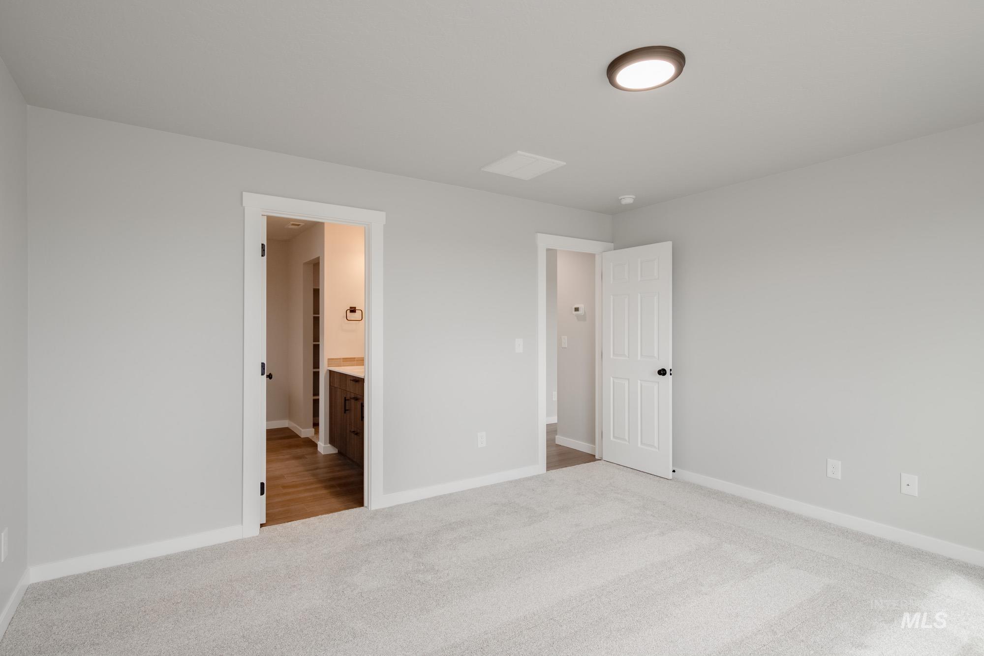 Unfurnished bedroom featuring light carpet and connected bathroom