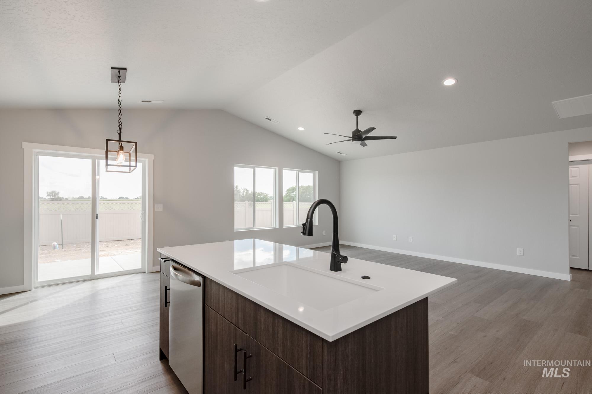 Kitchen featuring dark brown cabinets, hanging light fixtures, dishwasher, open floor plan, and light wood-type flooring