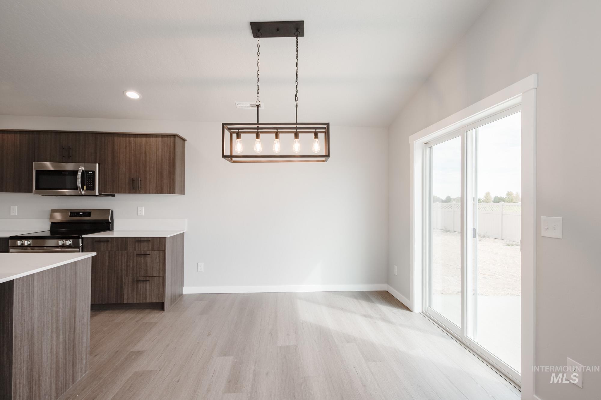 Kitchen featuring decorative light fixtures, light wood-style floors, appliances with stainless steel finishes, modern cabinets, and recessed lighting