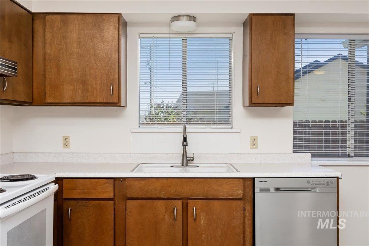 Kitchen featuring dishwasher, brown cabinets, healthy amount of natural light, and light countertops