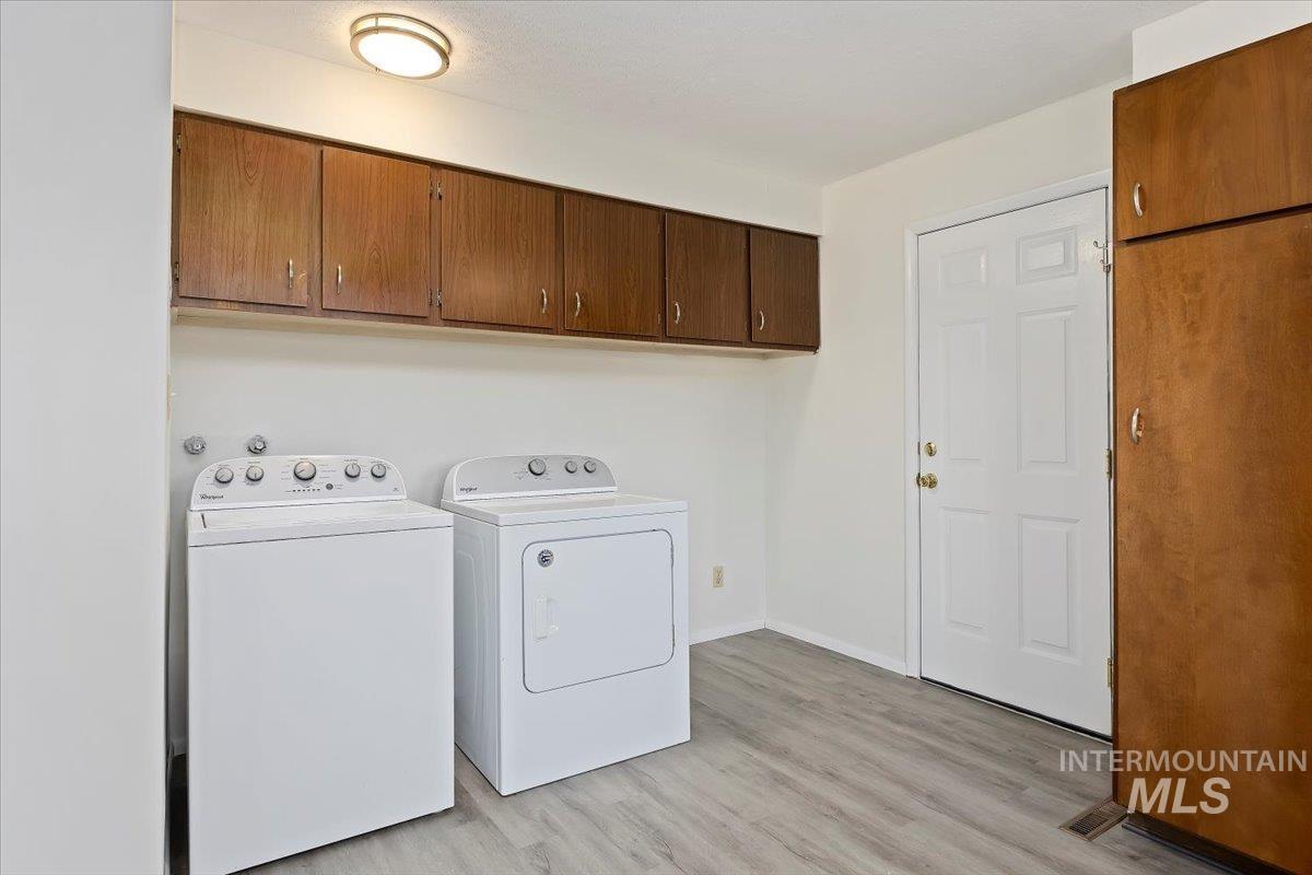 Washroom featuring cabinet space, light wood-style floors, and washer and dryer