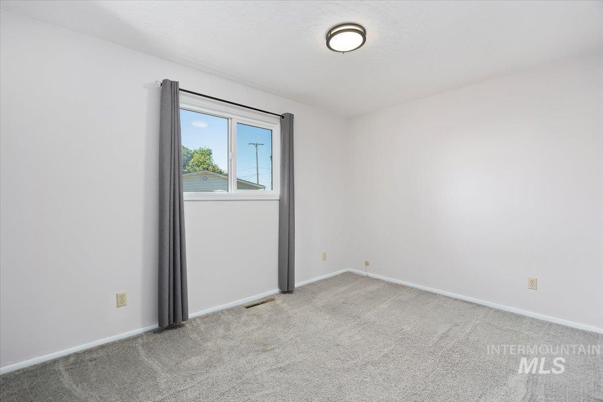 Spare room featuring light colored carpet and baseboards