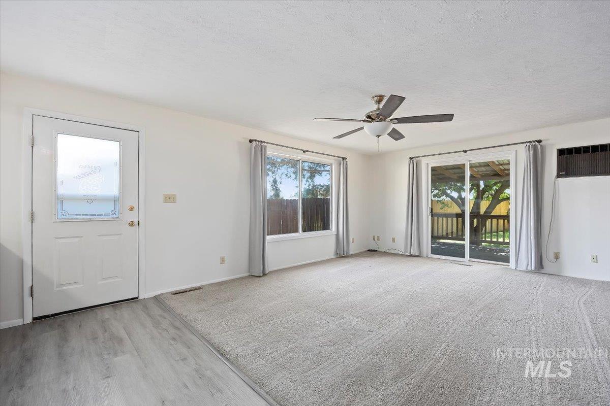 Foyer entrance with a ceiling fan, a textured ceiling, light wood-style flooring, and a wall mounted AC