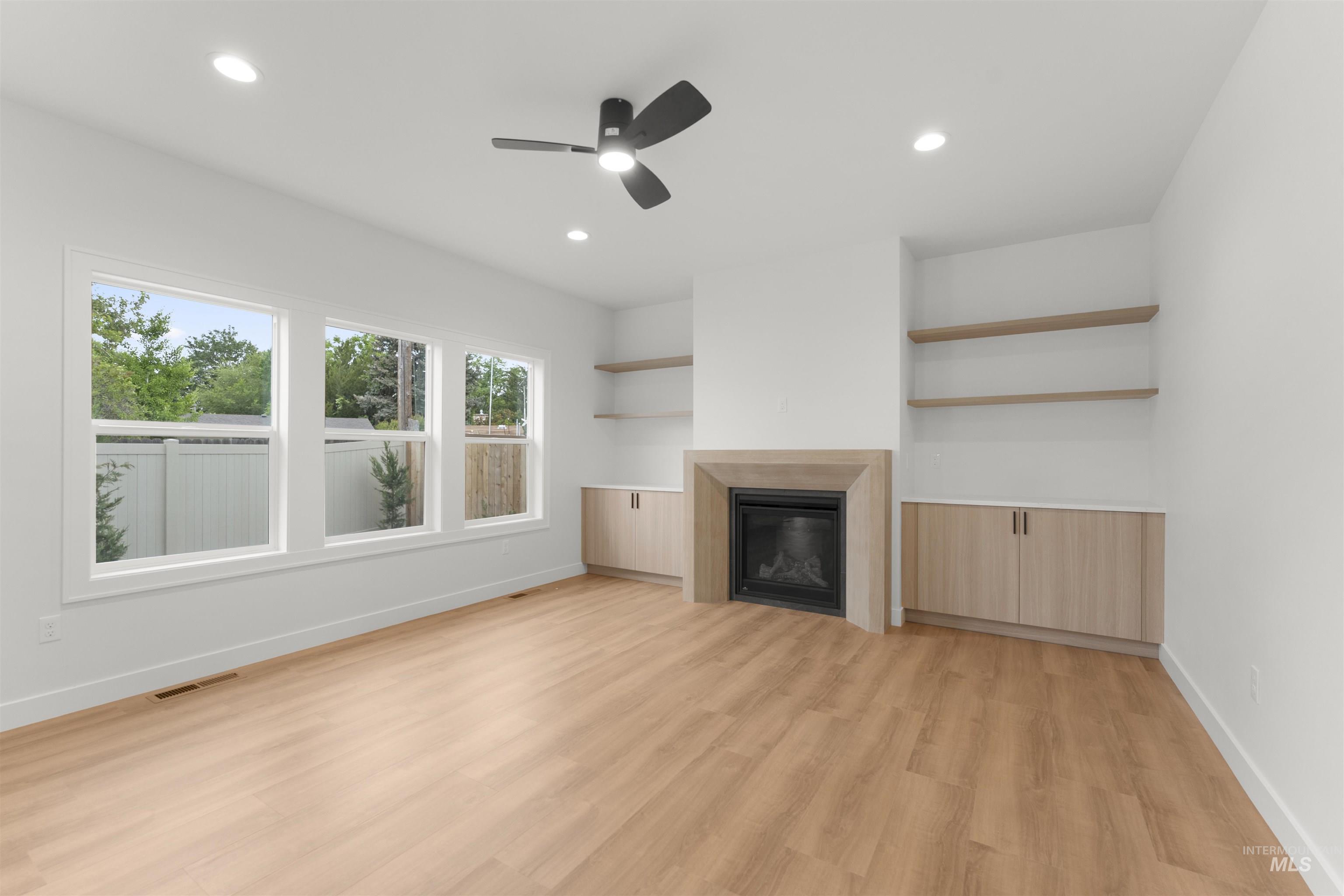 Unfurnished living room with a glass covered fireplace, light wood-type flooring, recessed lighting, and ceiling fan