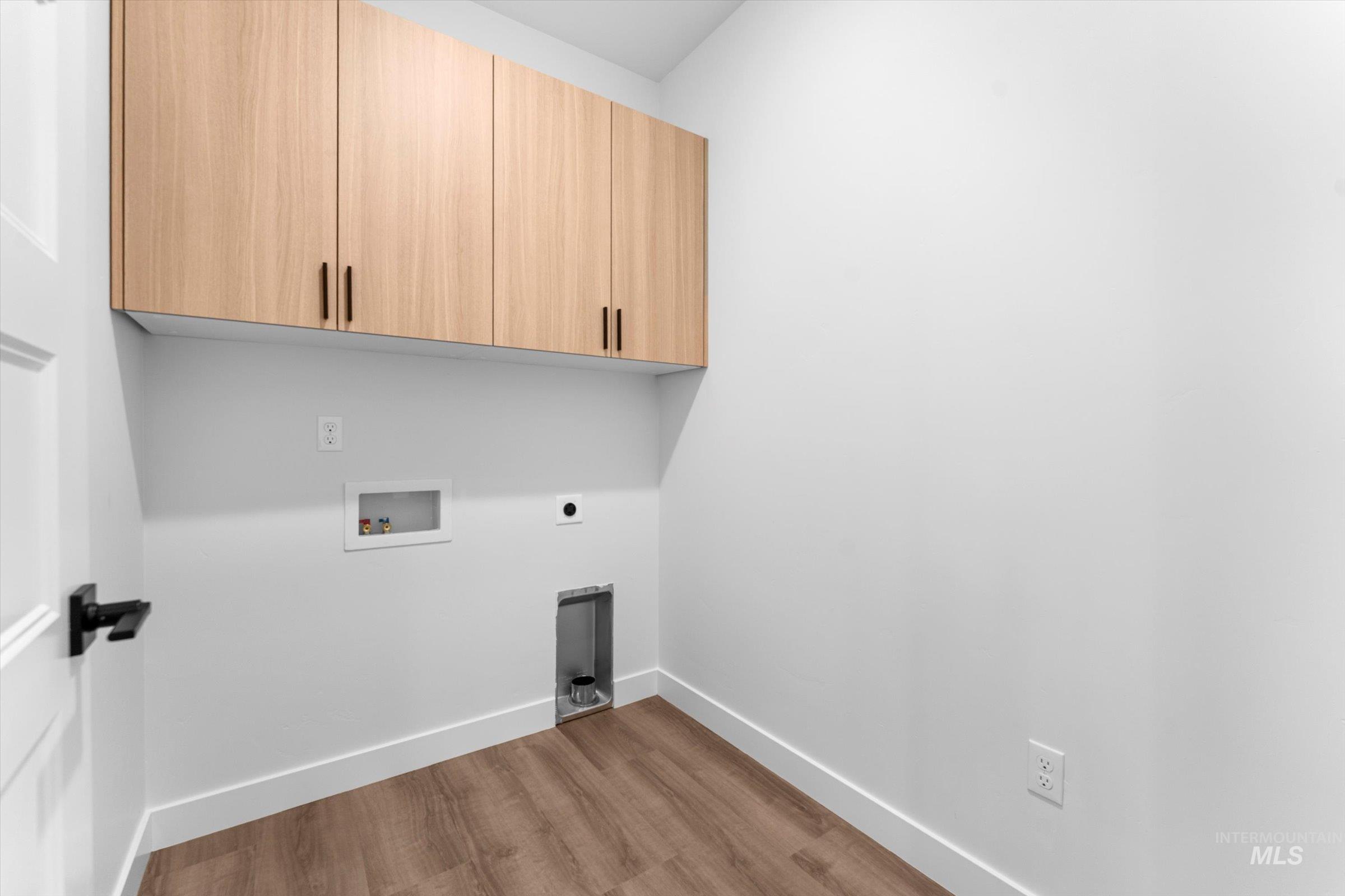 Laundry area featuring light wood-style flooring, hookup for a washing machine, cabinet space, and electric dryer hookup