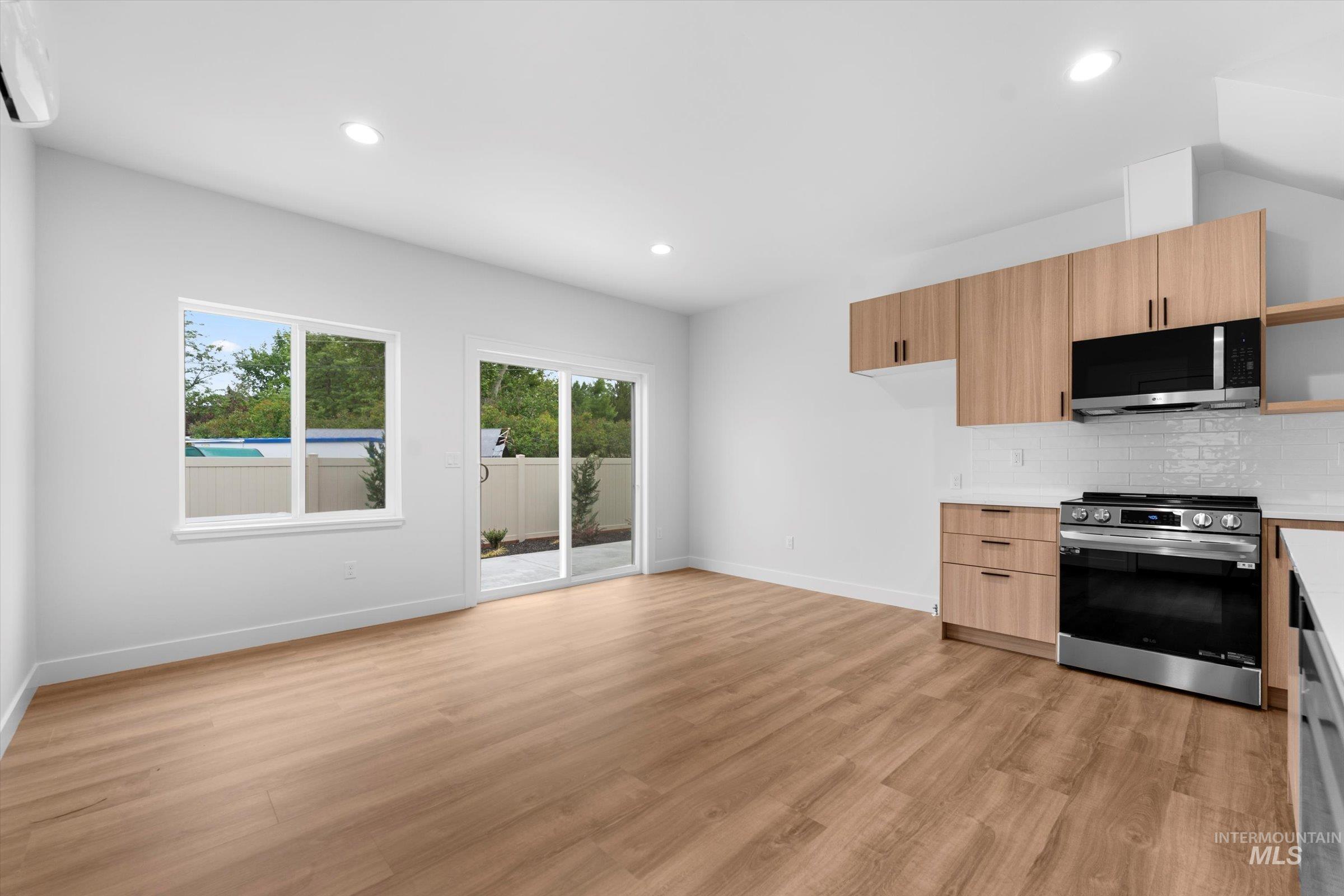 Kitchen with modern cabinets, light countertops, stainless steel appliances, backsplash, and recessed lighting