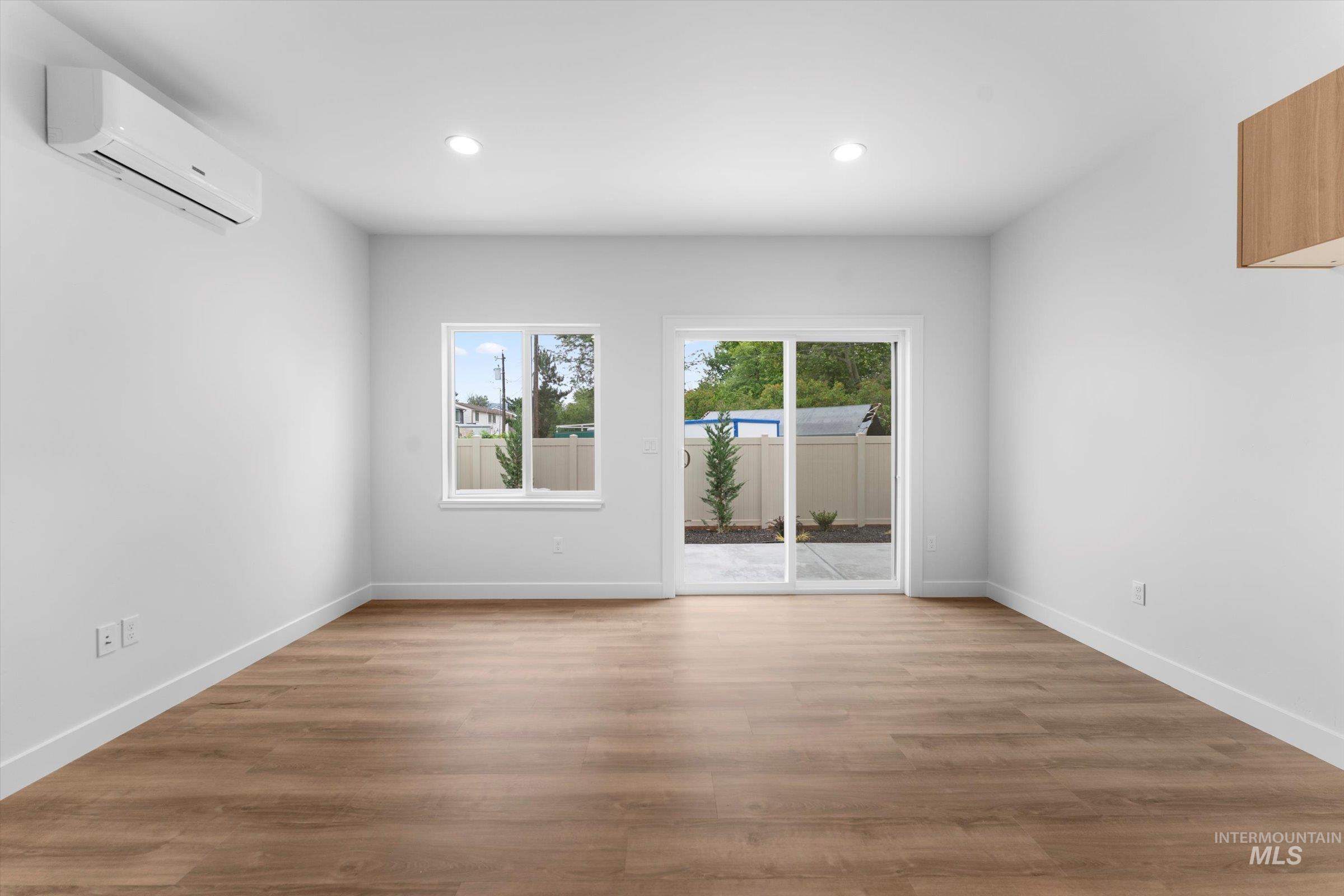 Spare room featuring light wood-type flooring, an AC wall unit, and recessed lighting