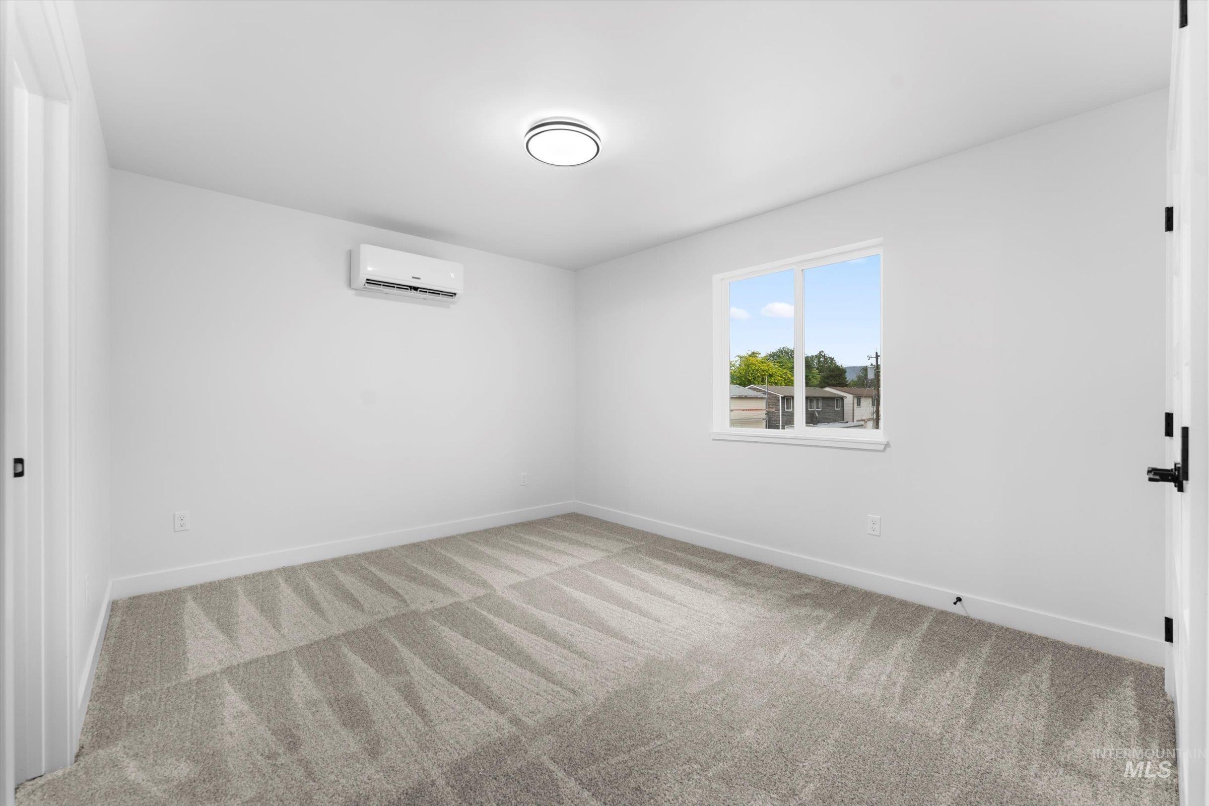 Spare room featuring light carpet and a wall mounted AC