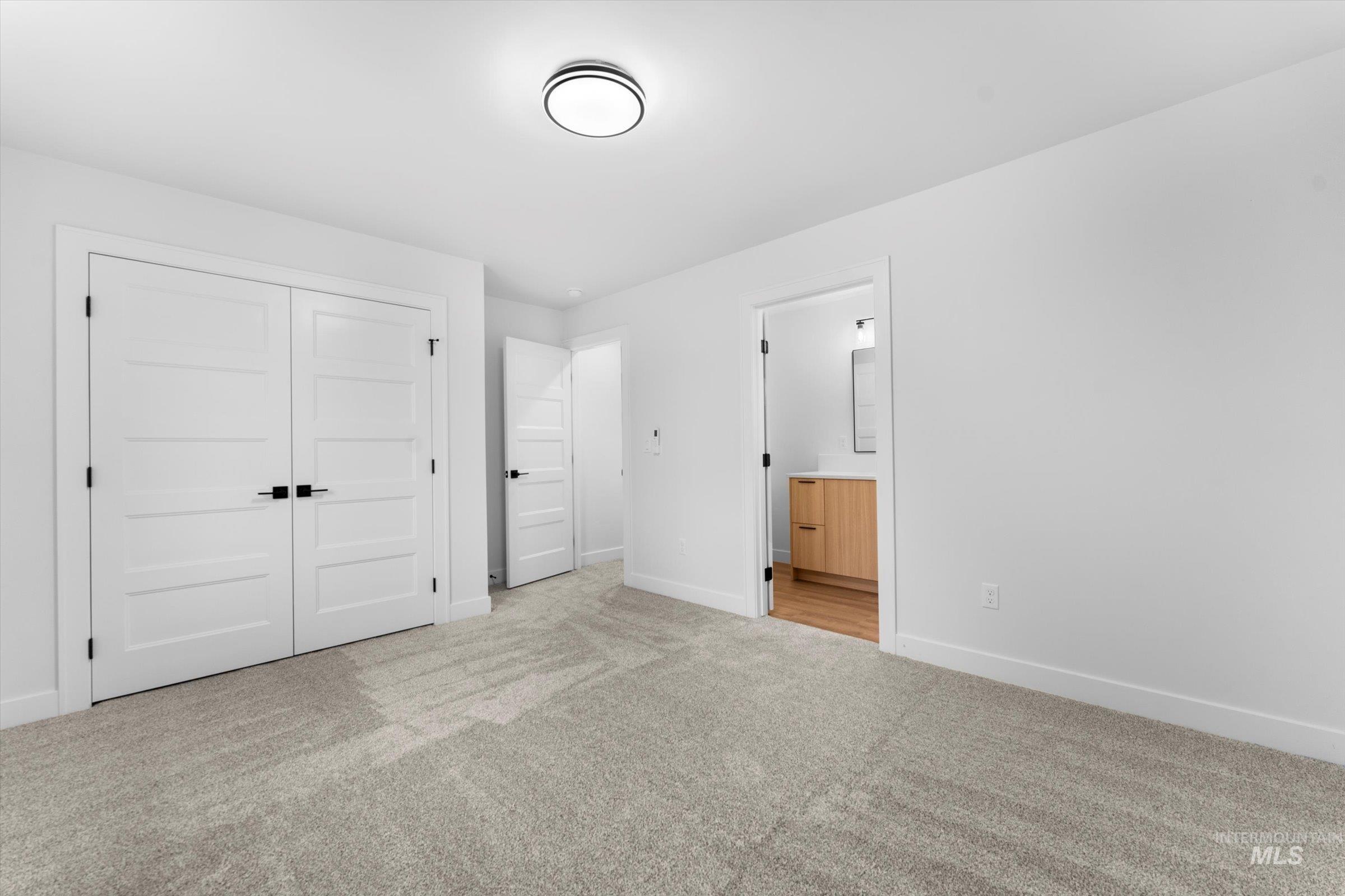 Unfurnished bedroom with carpet flooring, a closet, and ensuite bathroom