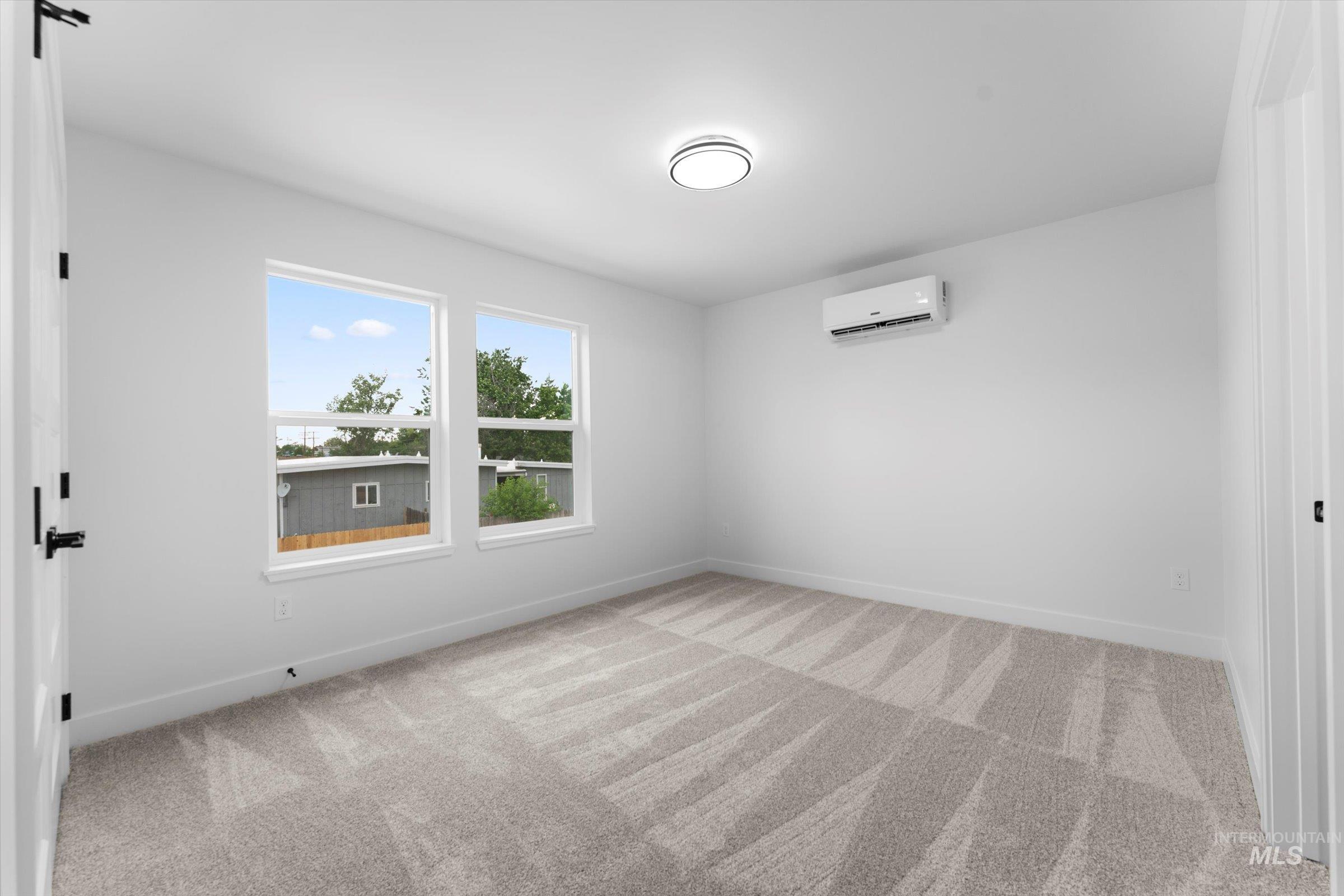 Unfurnished room with light colored carpet and a wall mounted air conditioner