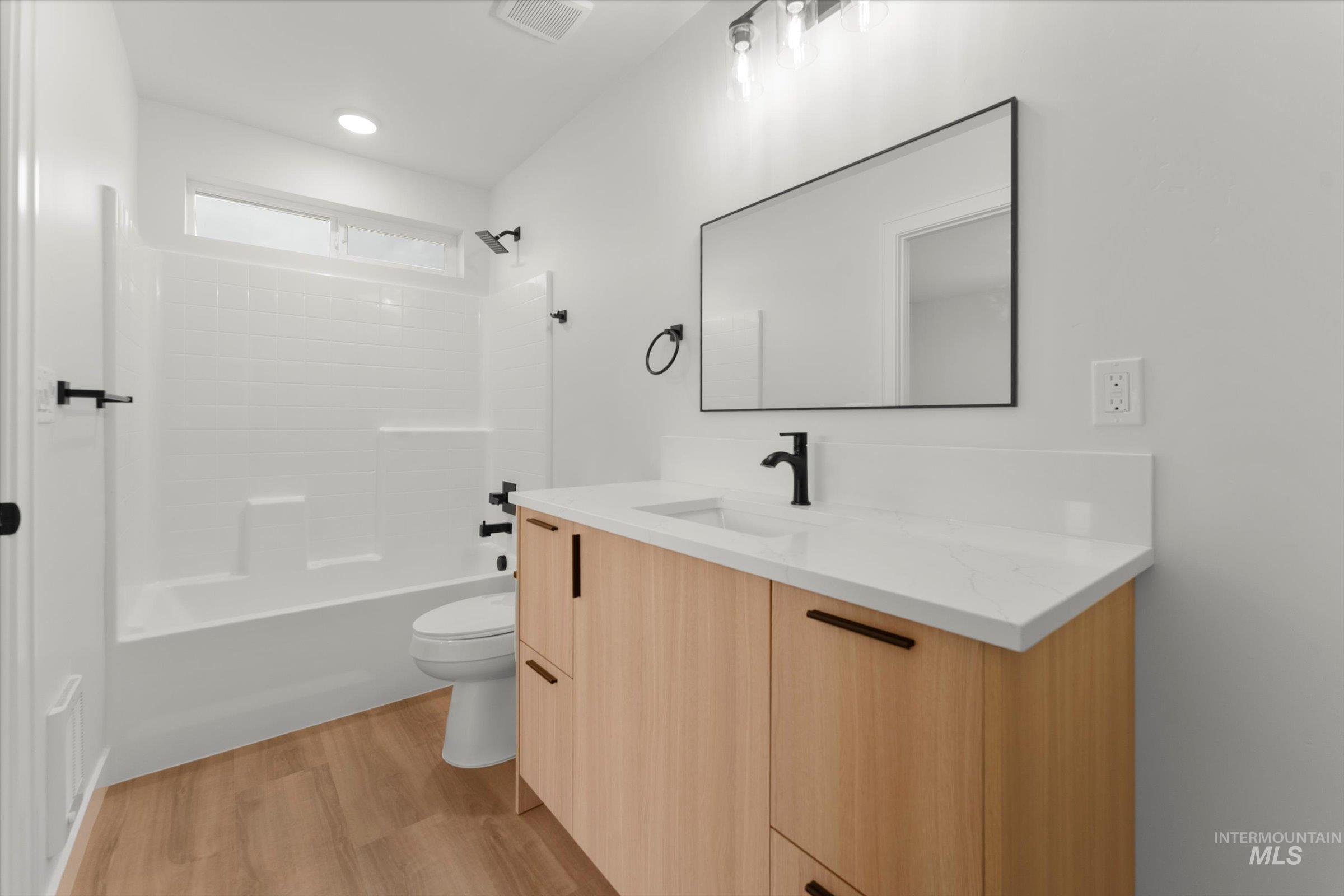 Full bathroom with bathing tub / shower combination, light wood finished floors, vanity, and recessed lighting