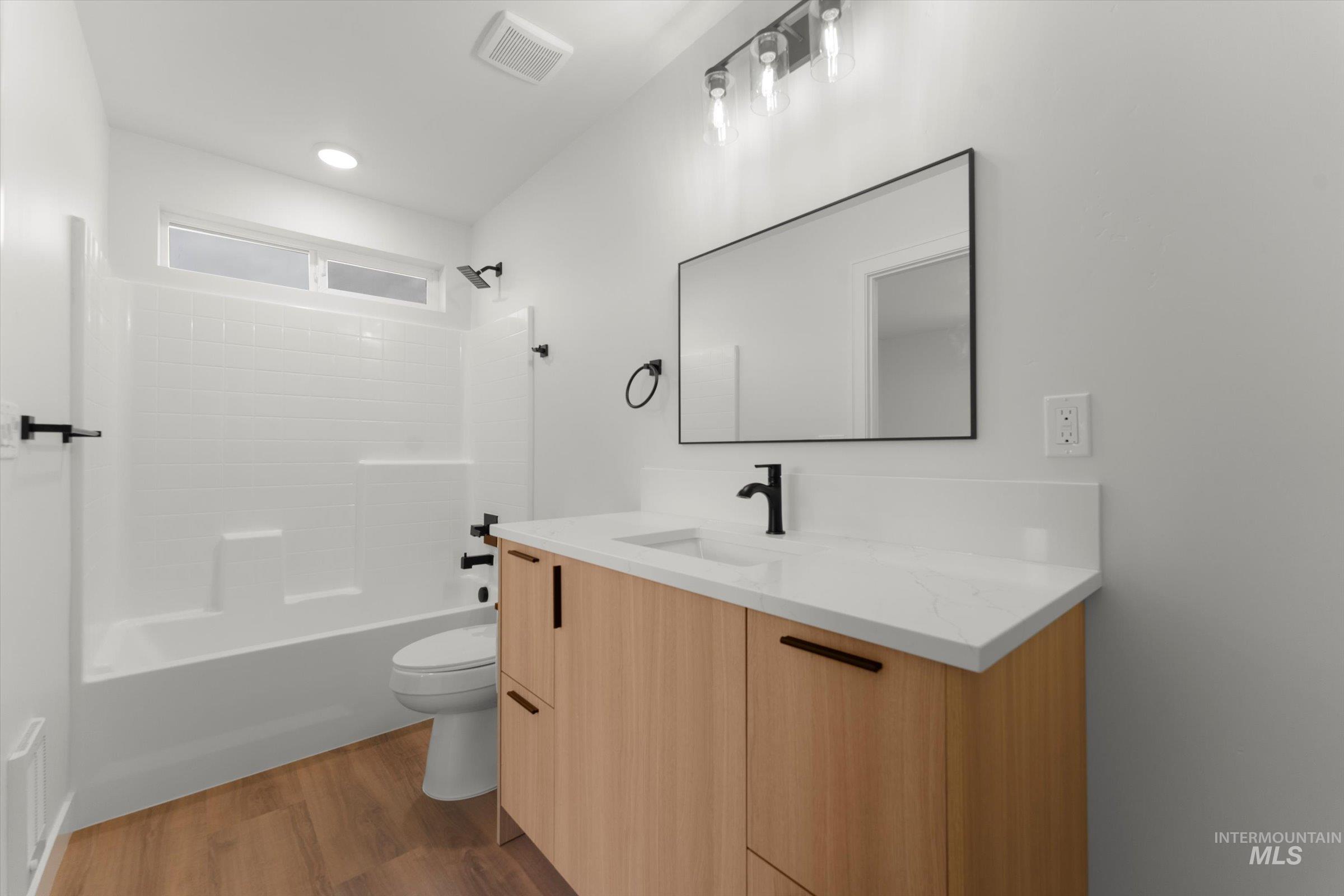 Full bathroom with shower / tub combination, dark wood-type flooring, and vanity