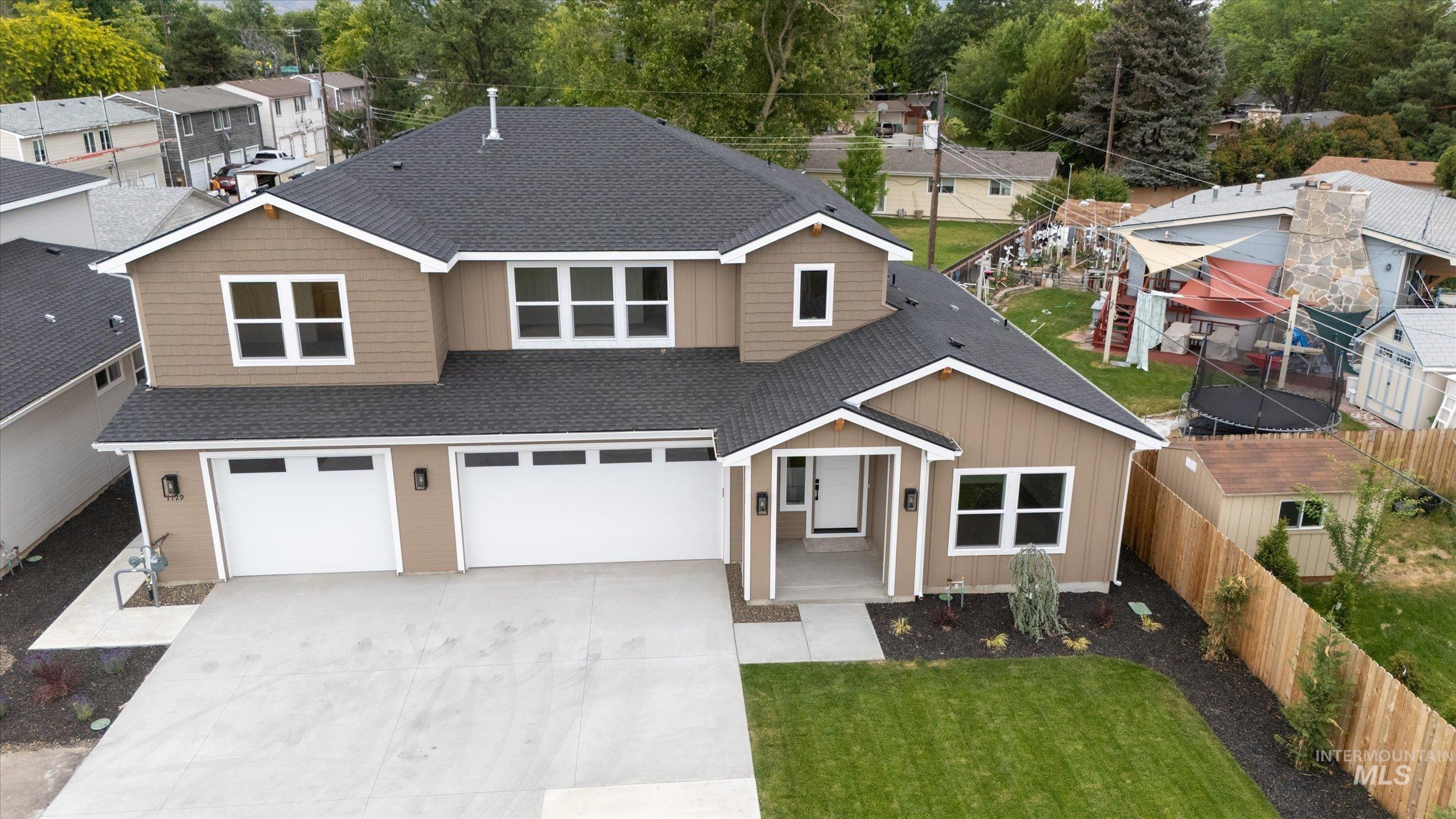 View of front of home featuring roof with shingles, driveway, an attached garage, and a residential view