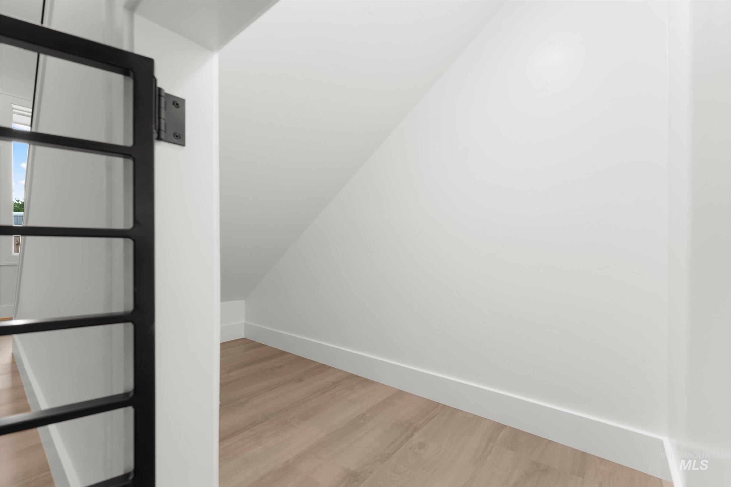 Bonus room featuring light wood-style floors and lofted ceiling