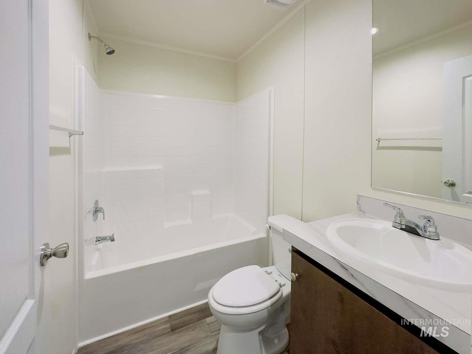 Bathroom featuring shower / tub combination, vanity, dark wood finished floors, and ornamental molding