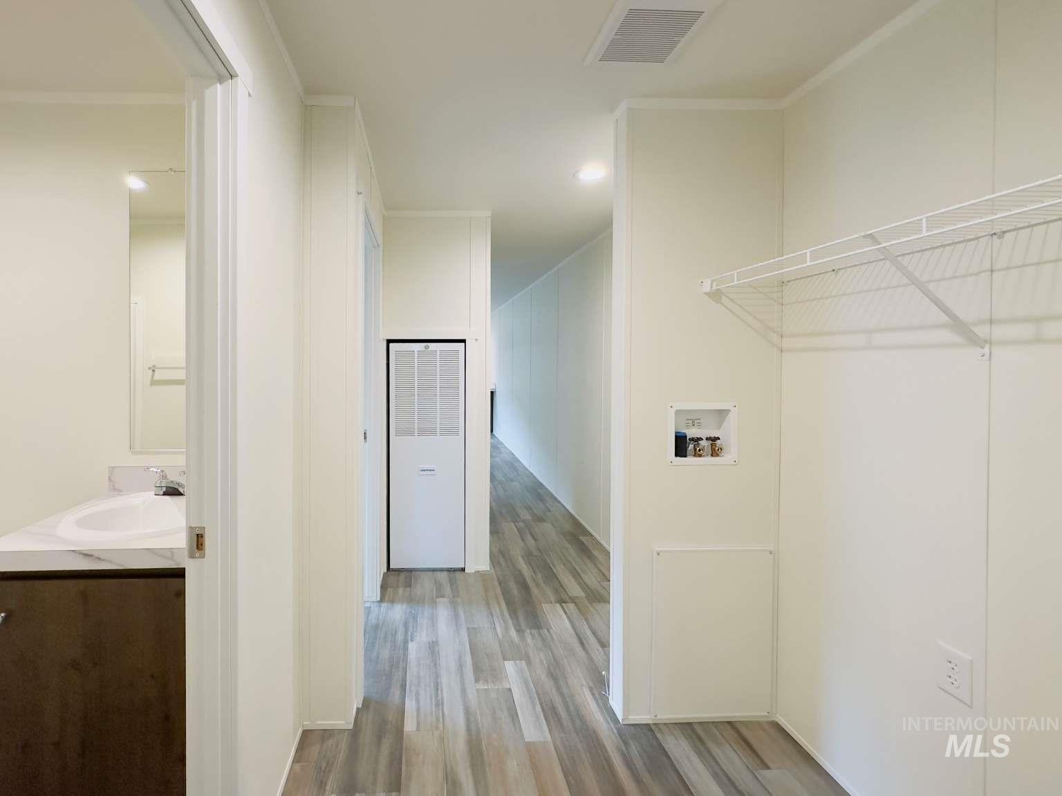 Laundry area with wood finished floors, a heating unit, and hookup for a washing machine