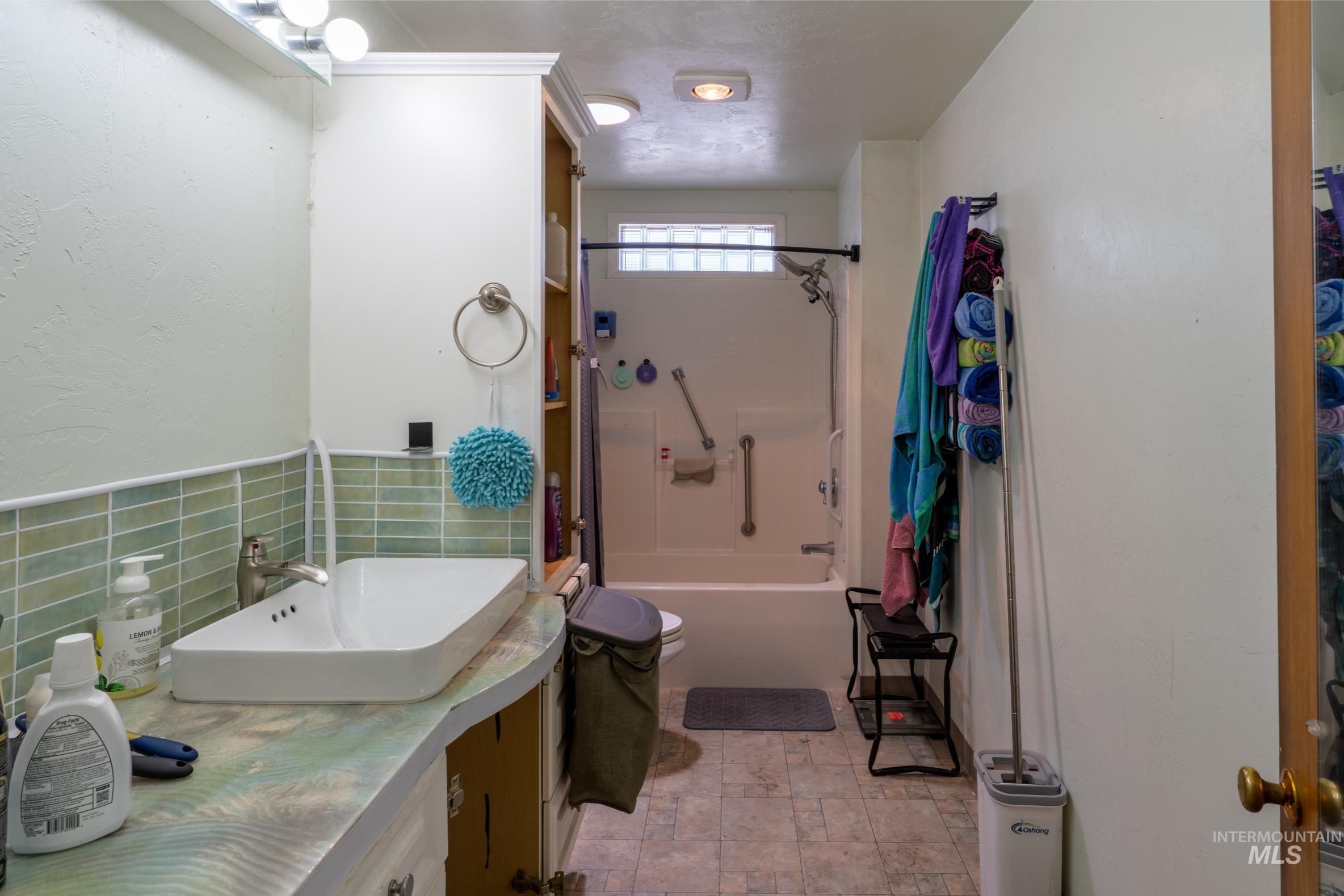 Bathroom featuring shower / bath combination, vanity, tile walls, and a textured wall