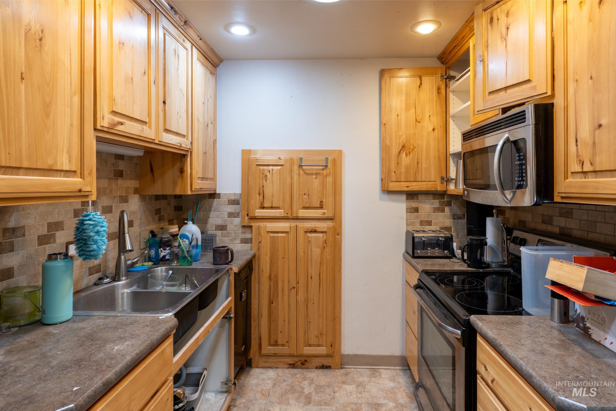 Kitchen with tasteful backsplash, appliances with stainless steel finishes, and dark countertops