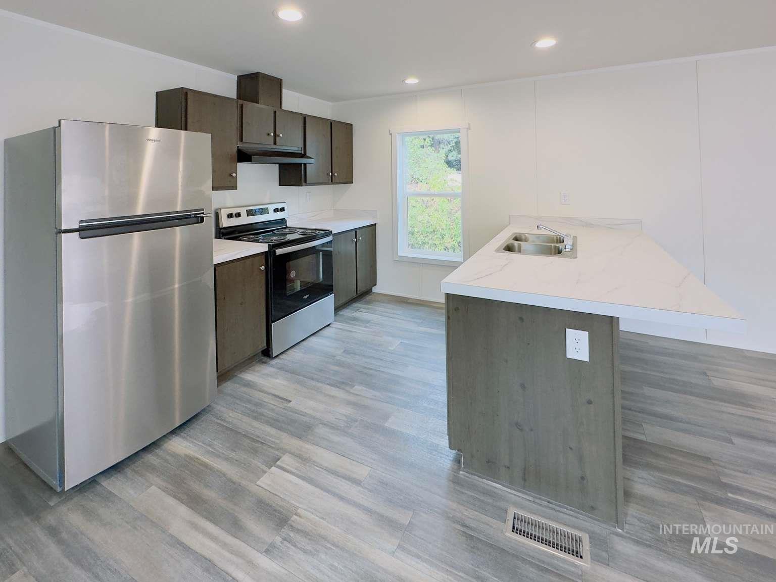 Kitchen with appliances with stainless steel finishes, a peninsula, light countertops, recessed lighting, and a kitchen bar