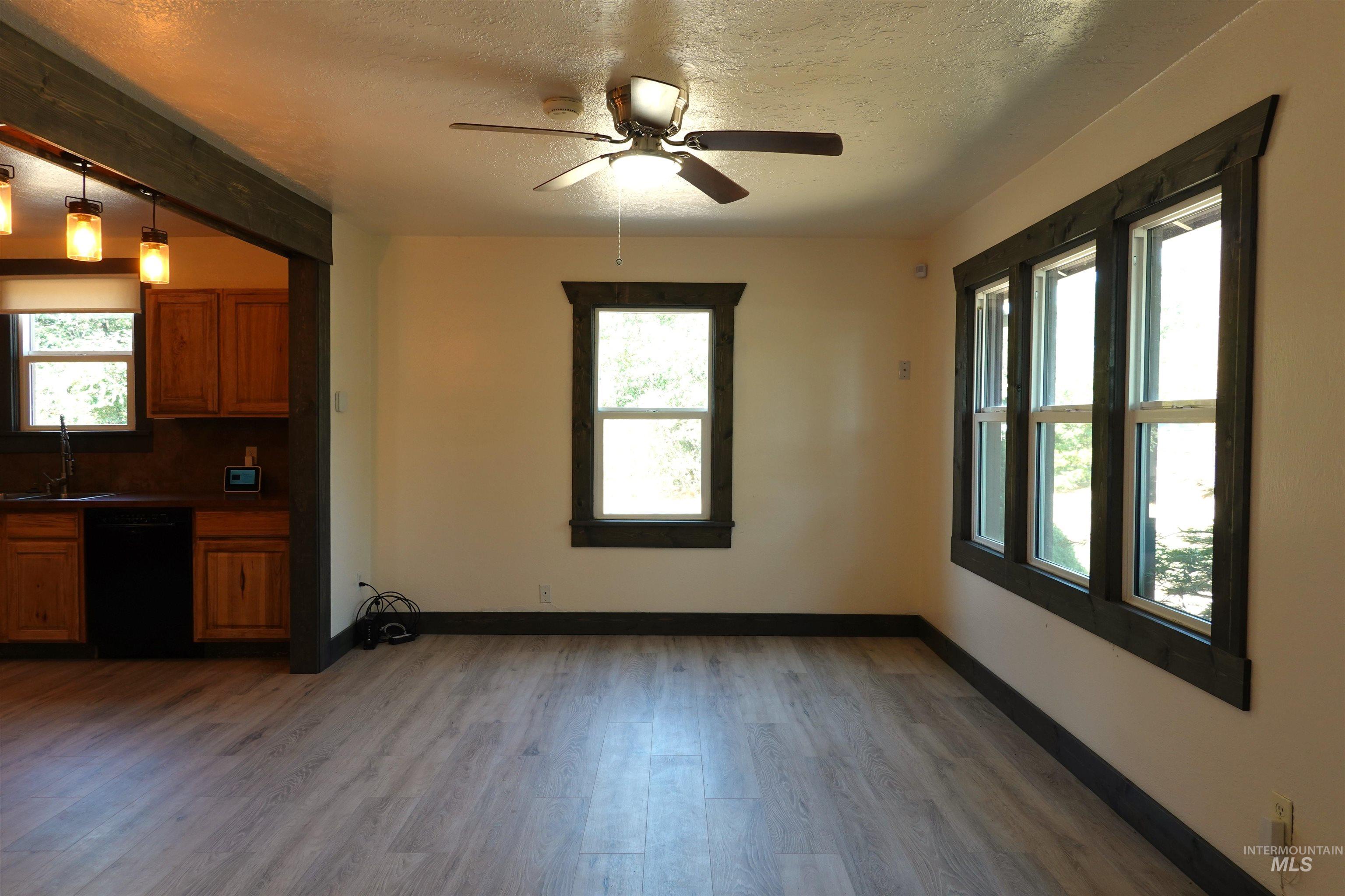 Kitchen featuring brown cabinetry, light wood-style floors, dark countertops, plenty of natural light, and a textured ceiling