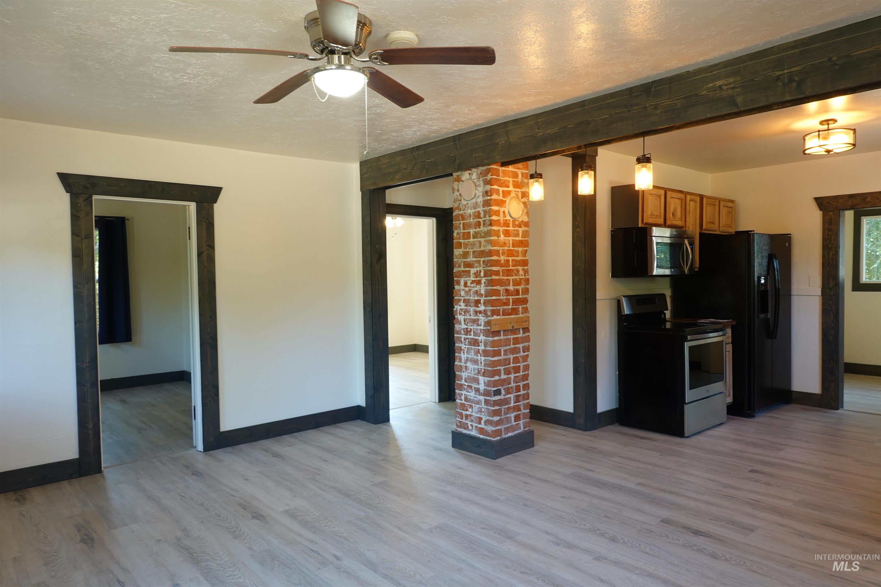 Unfurnished living room with light wood-type flooring, a textured ceiling, and ceiling fan