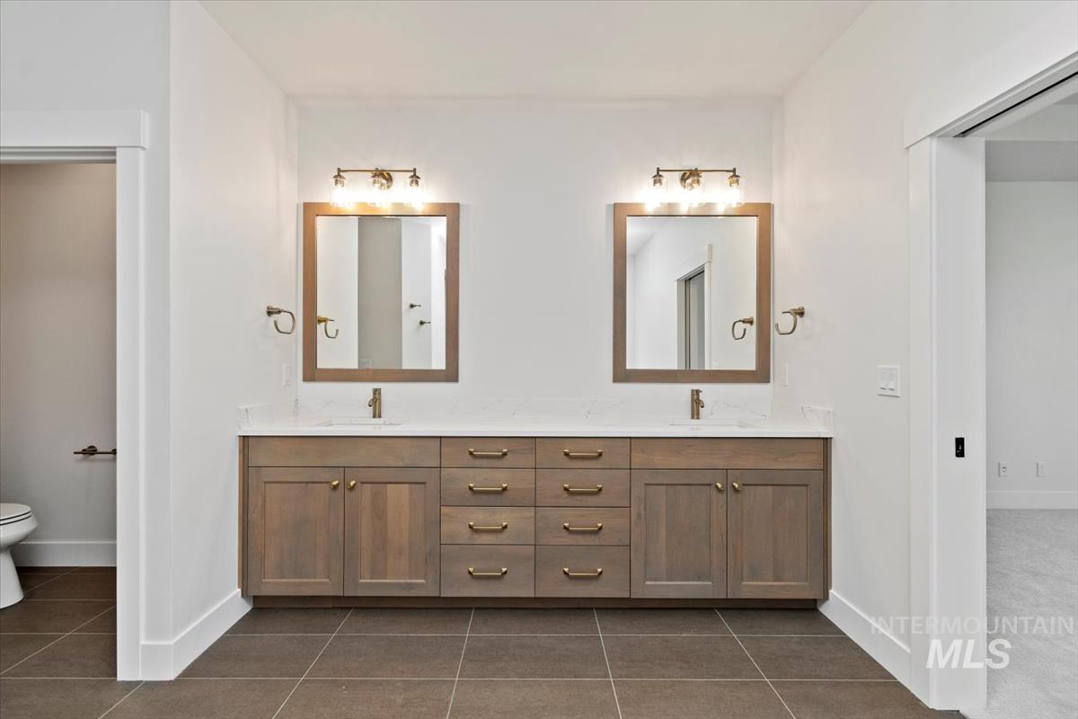 Bathroom with double vanity and dark tile patterned floors