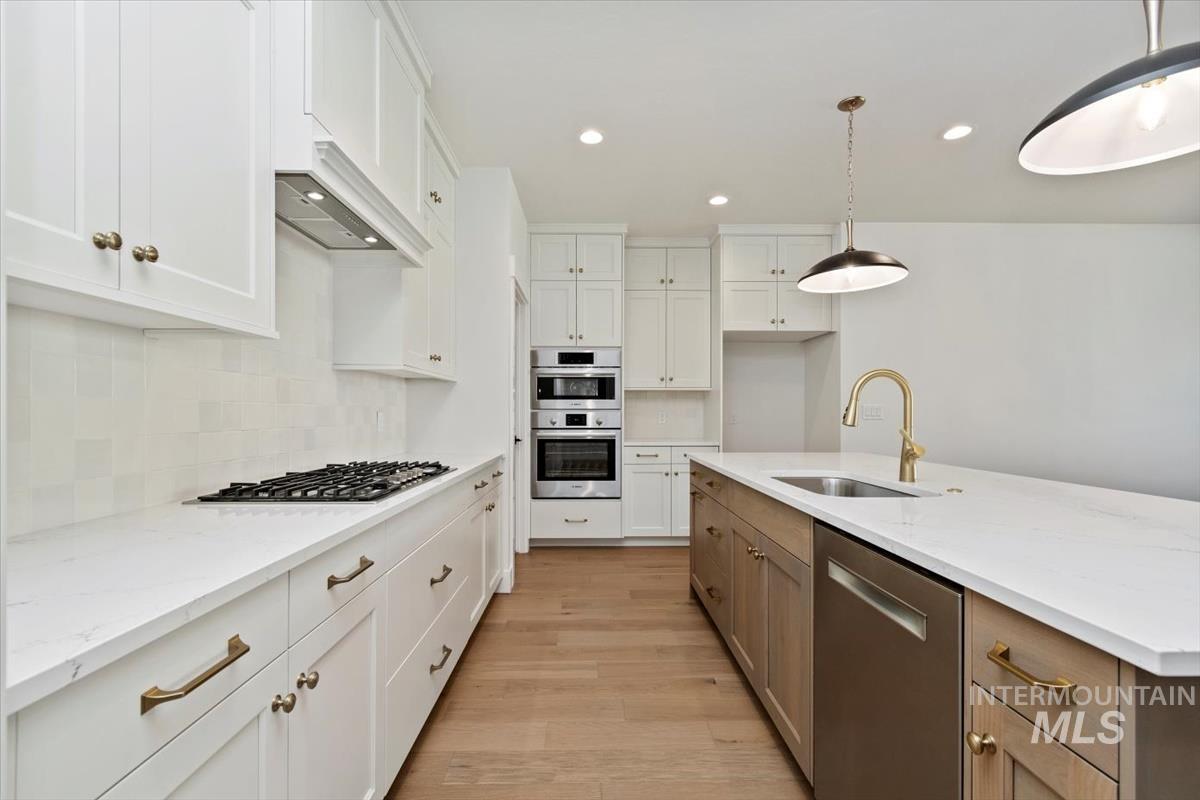Kitchen featuring appliances with stainless steel finishes, white cabinetry, recessed lighting, light stone countertops, and tasteful backsplash