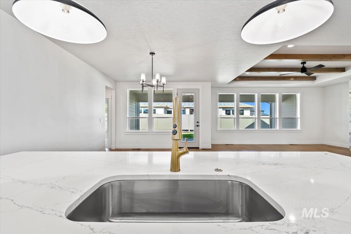 Kitchen with light stone countertops, open floor plan, wood finished floors, and pendant lighting