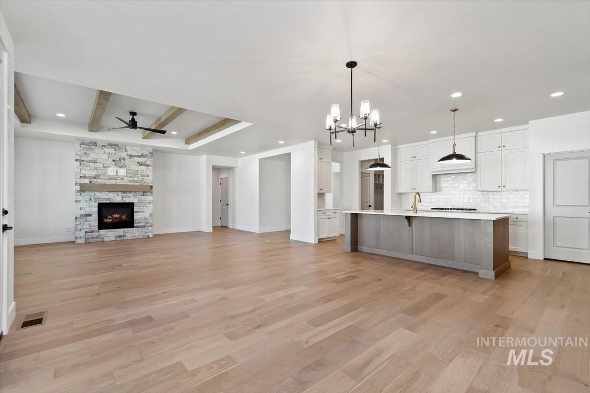 Kitchen with open floor plan, white cabinetry, light wood finished floors, decorative light fixtures, and a fireplace