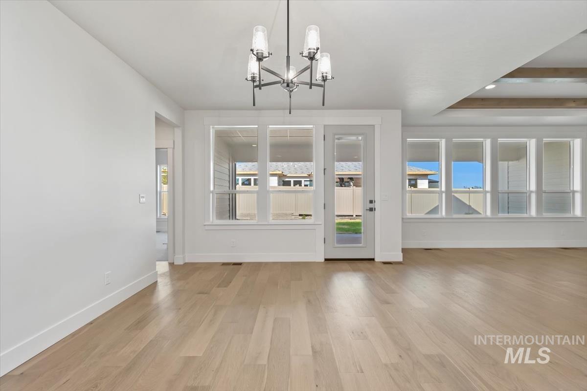 Unfurnished dining area with light wood-style floors, a chandelier, and a tray ceiling