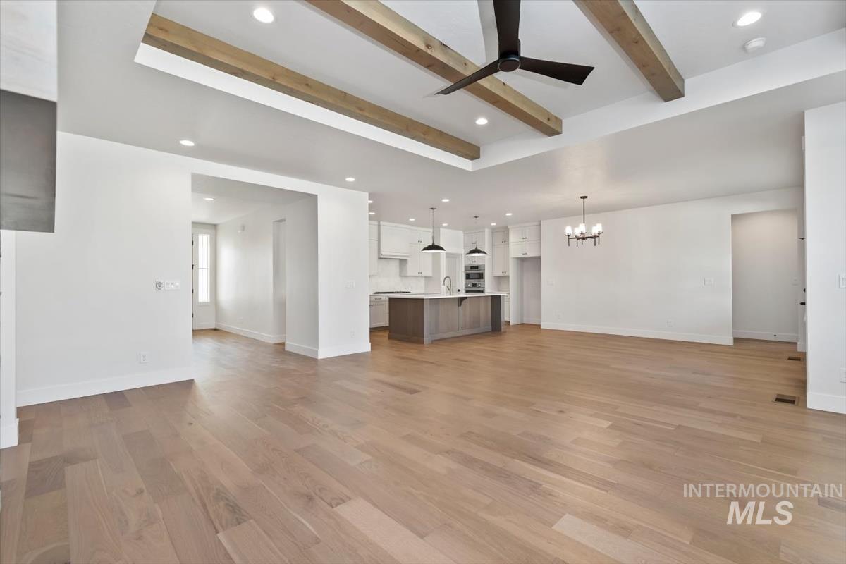 Unfurnished living room with recessed lighting, beam ceiling, a chandelier, light wood-type flooring, and ceiling fan
