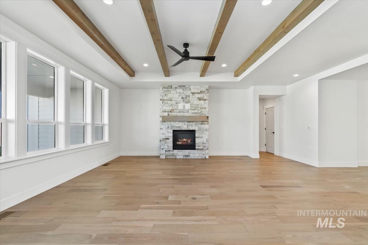 Unfurnished living room featuring a fireplace, recessed lighting, light wood finished floors, beam ceiling, and a ceiling fan