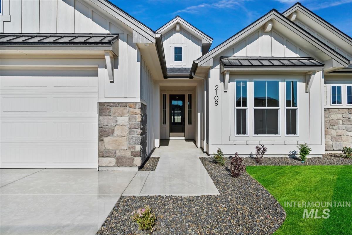 Doorway to property featuring a standing seam roof, stone siding, board and batten siding, and a metal roof