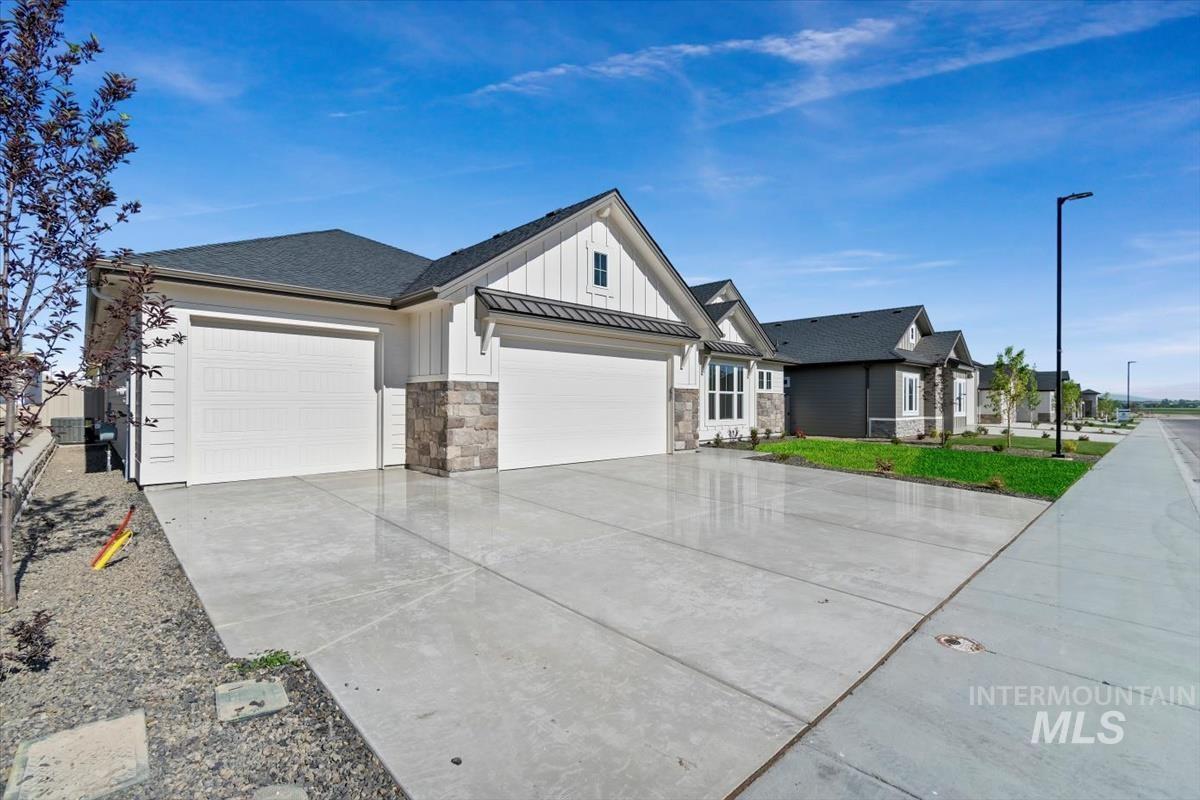 Modern farmhouse with board and batten siding, a standing seam roof, an attached garage, concrete driveway, and a metal roof
