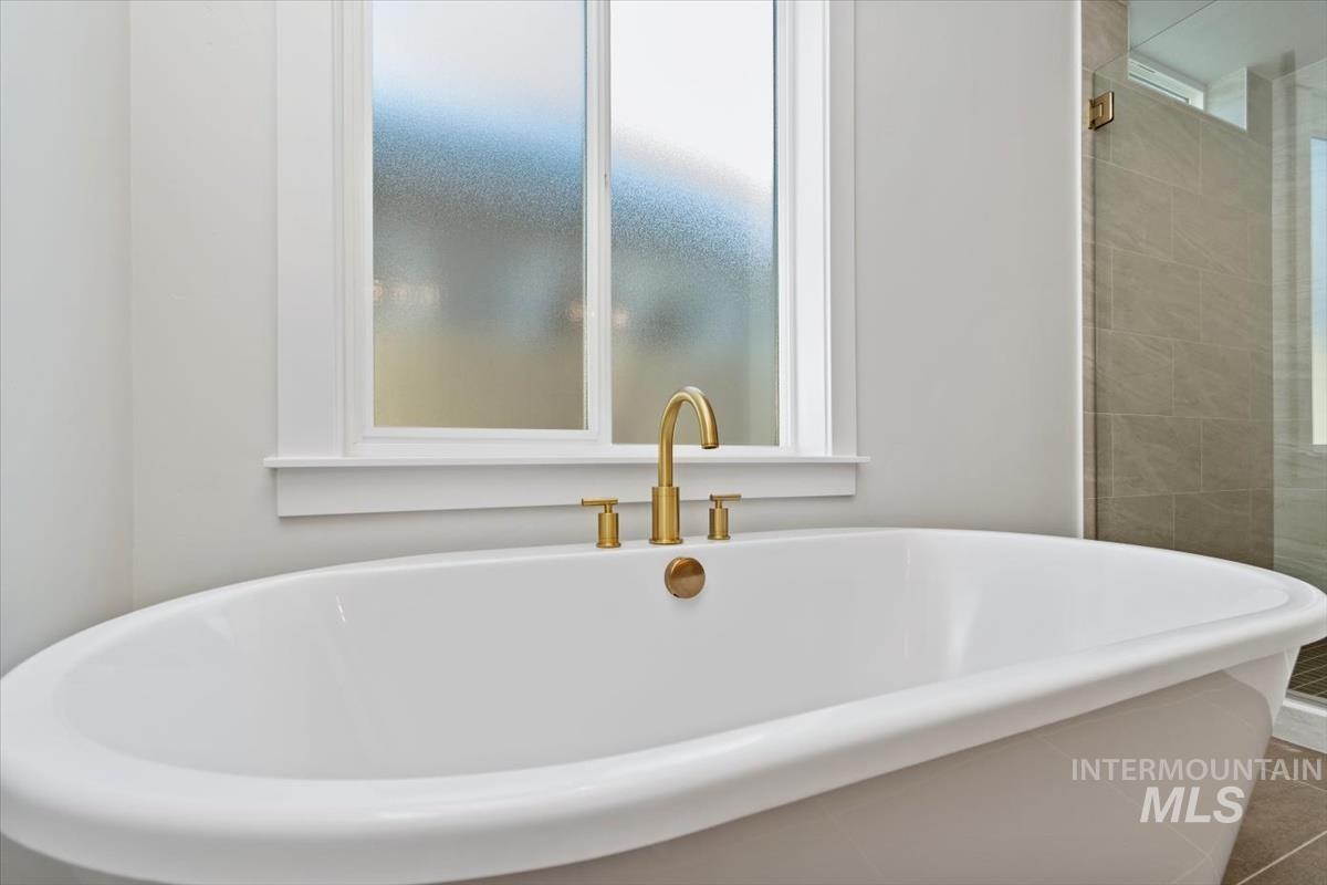 Bathroom with a freestanding bath, plenty of natural light, and a shower stall