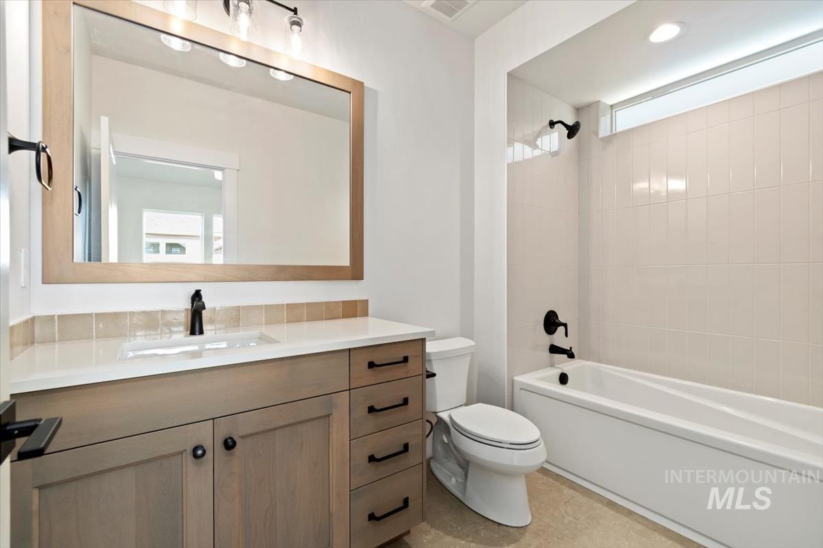Full bathroom featuring washtub / shower combination, vanity, and light tile patterned flooring