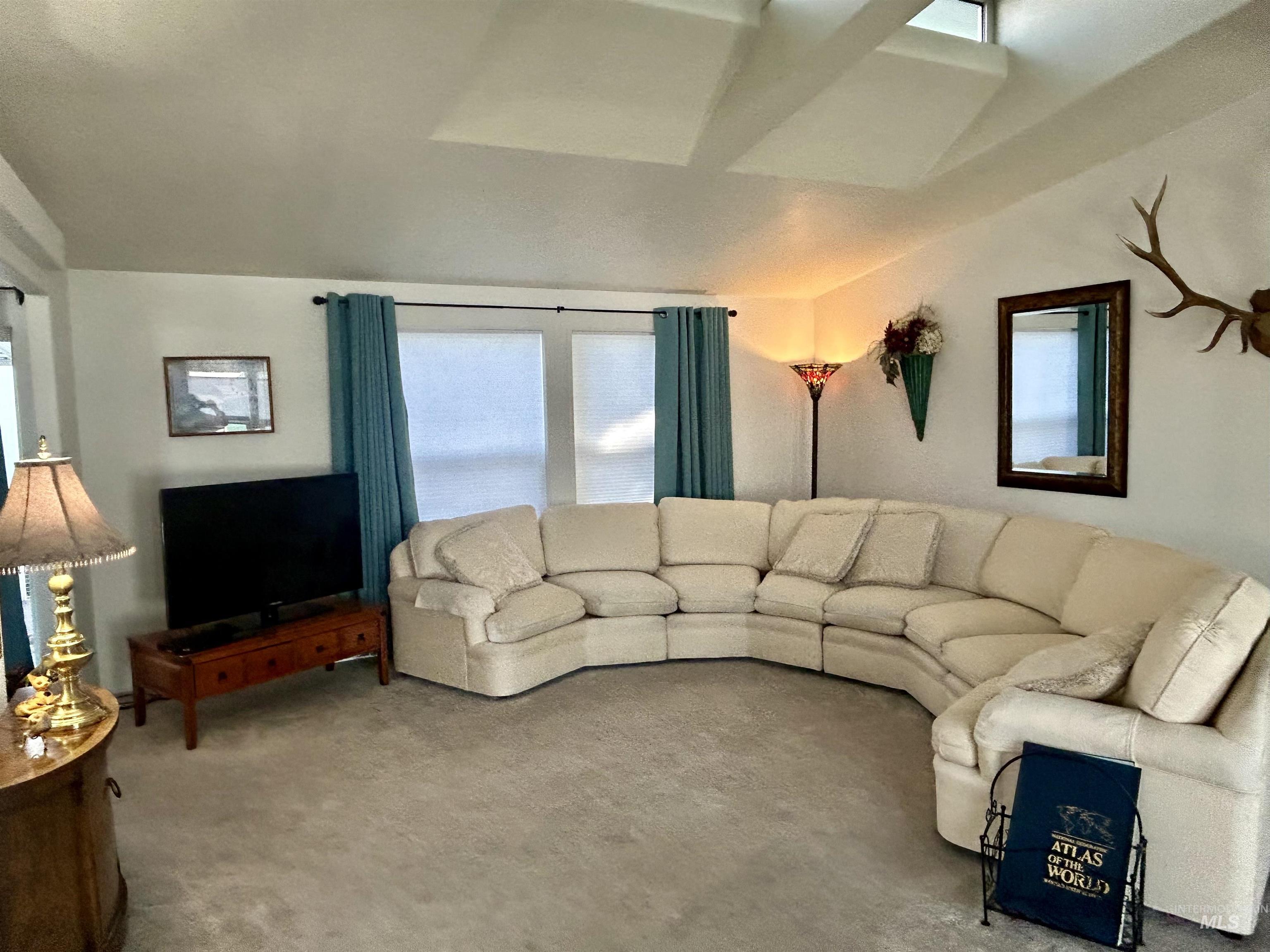 Carpeted living room with healthy amount of natural light and lofted ceiling
