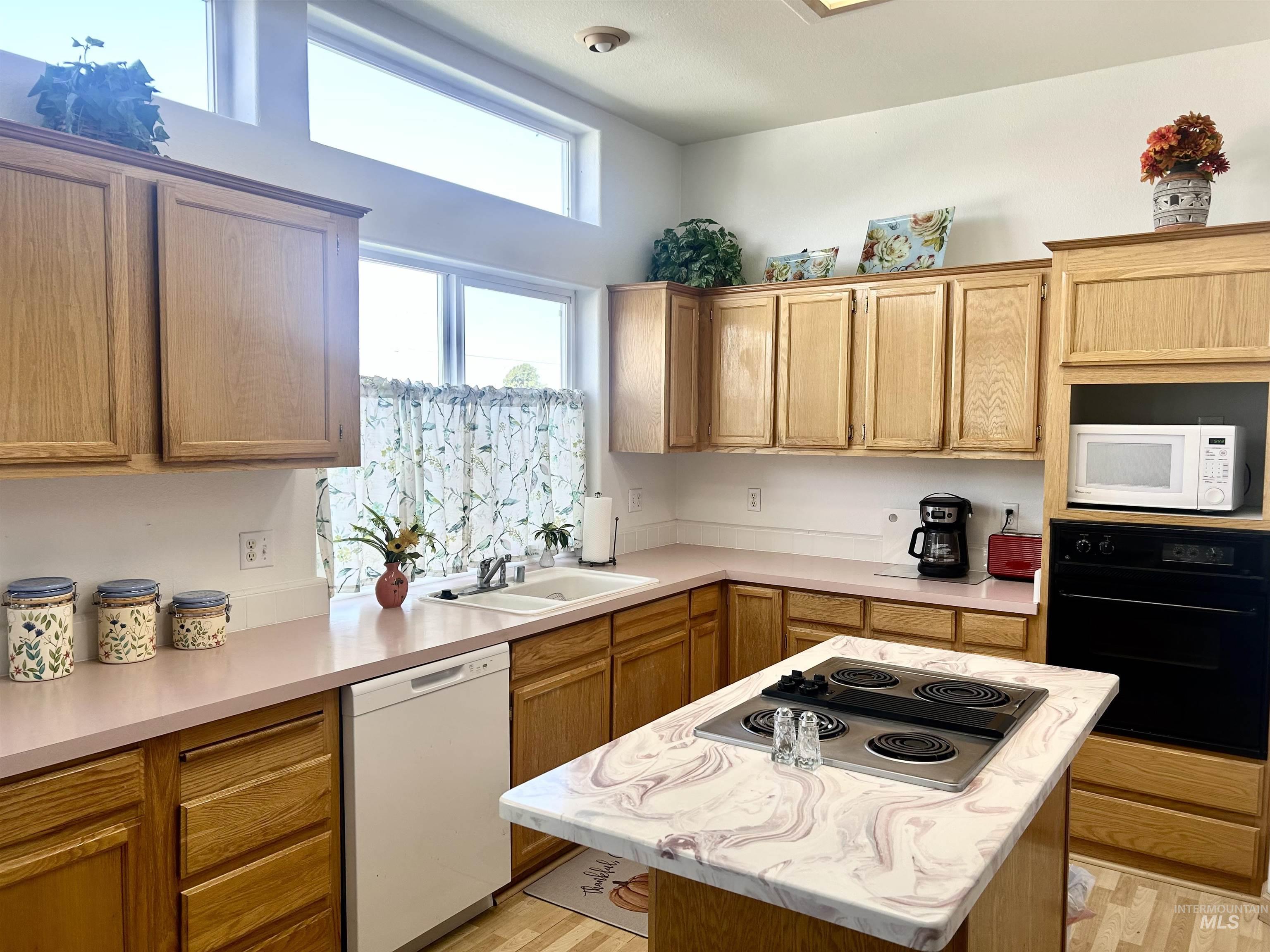 Kitchen with white appliances, a center island, light countertops, and light wood-type flooring